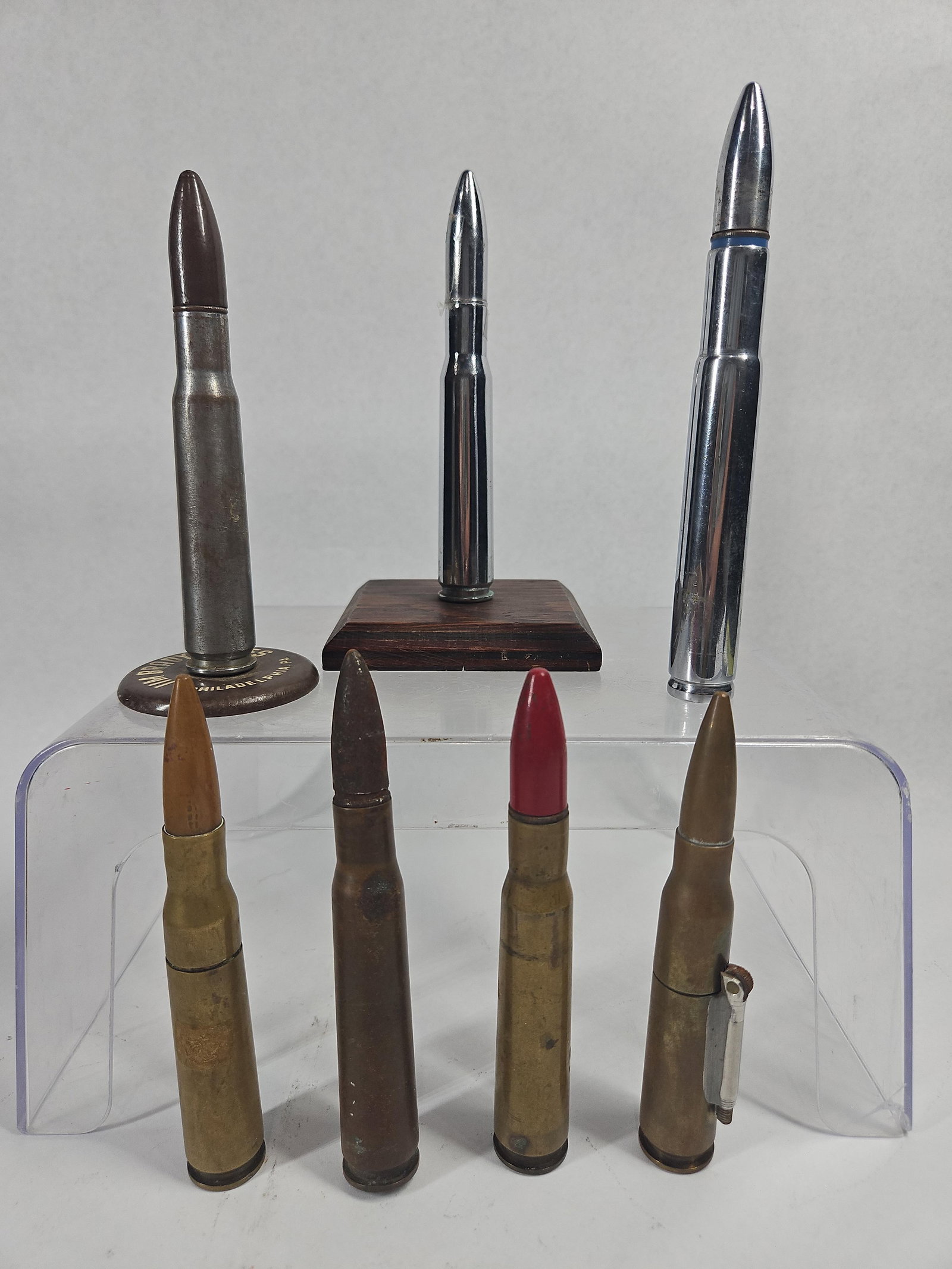 Set 7 .50 BMG Trench Art & Advertising: This lot features a collection of seven large-caliber cartridges, identified as .50 BMG, which have been repurposed into various advertising and trench art collectibles. The collection consists of