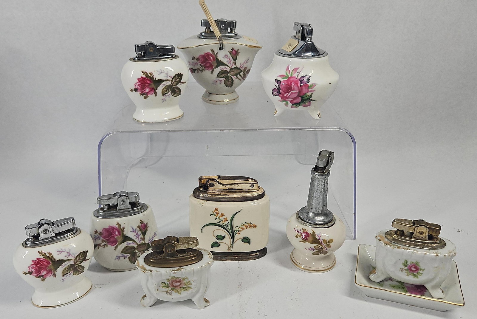 Vtg Japanese Porc. Table Lighters: An assortment of vintage table lighters featuring glazed porcelain bodies and mechanical metal inserts. The porcelain bodies are decorated with multicolored floral transfer patterns, primarily