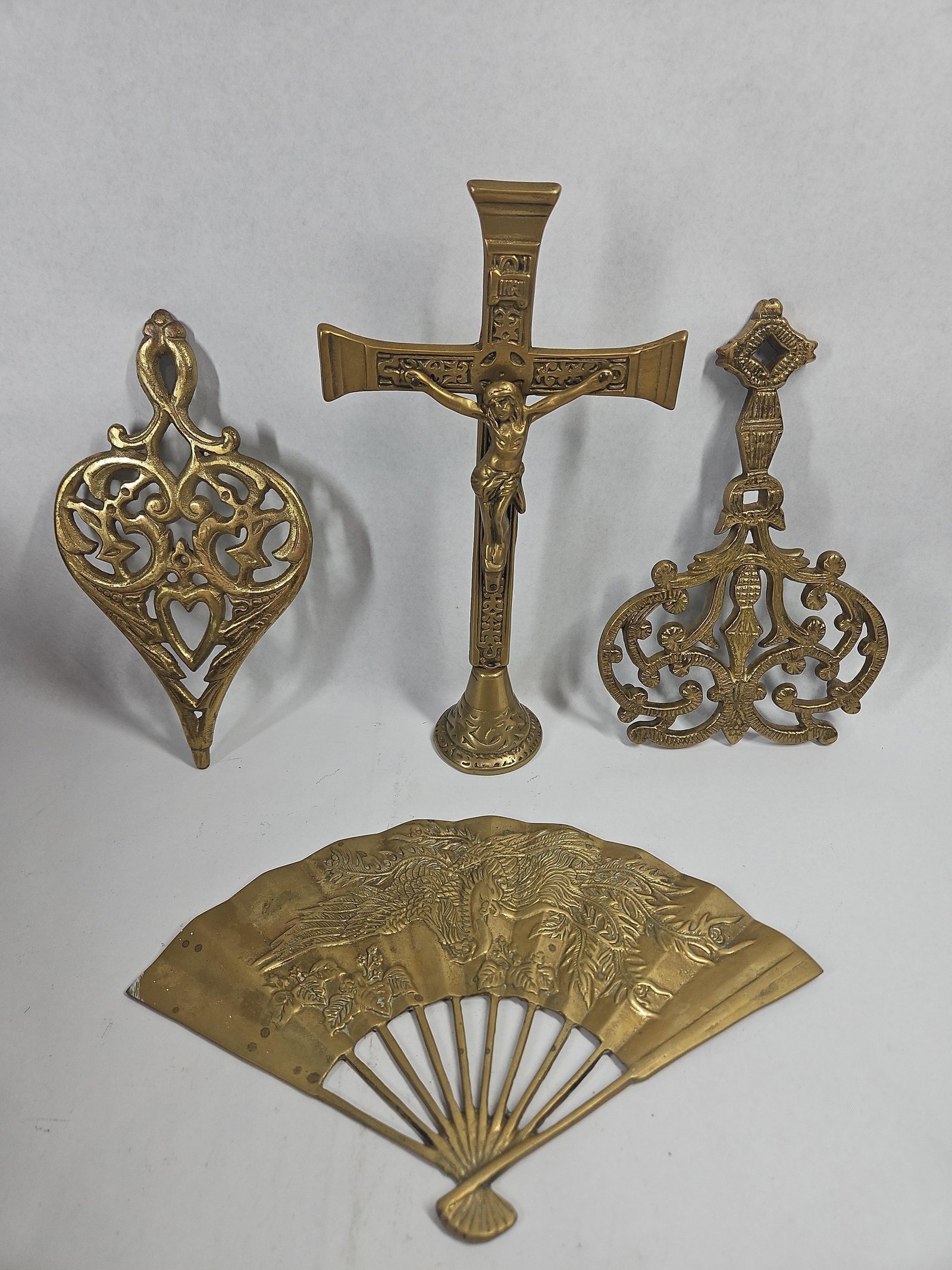 Wilton Brass Trivets & Altar Crucifix: This collection features several decorative items made of cast brass. An openwork trivet in a lyre or urn pattern with foliate scrolls stands on four integral peg feet; the reverse bears an impressed
