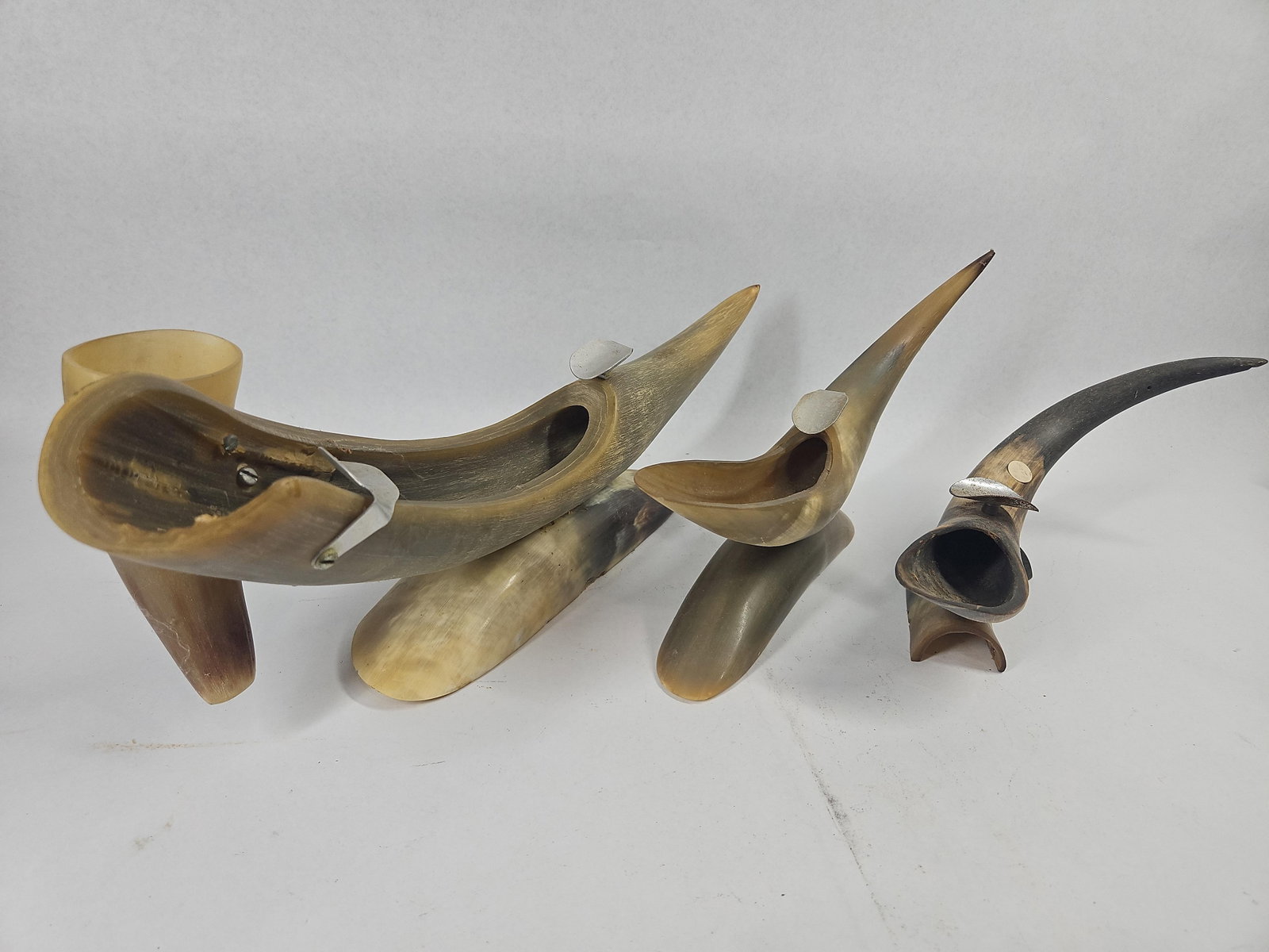Trio Mid-C. Bovine Horn Ashtrays: A group of three vintage mid-century ashtrays crafted from polished bovine horn. Each item features a section of natural horn carved to create a shallow well and is affixed to a secondary curved horn
