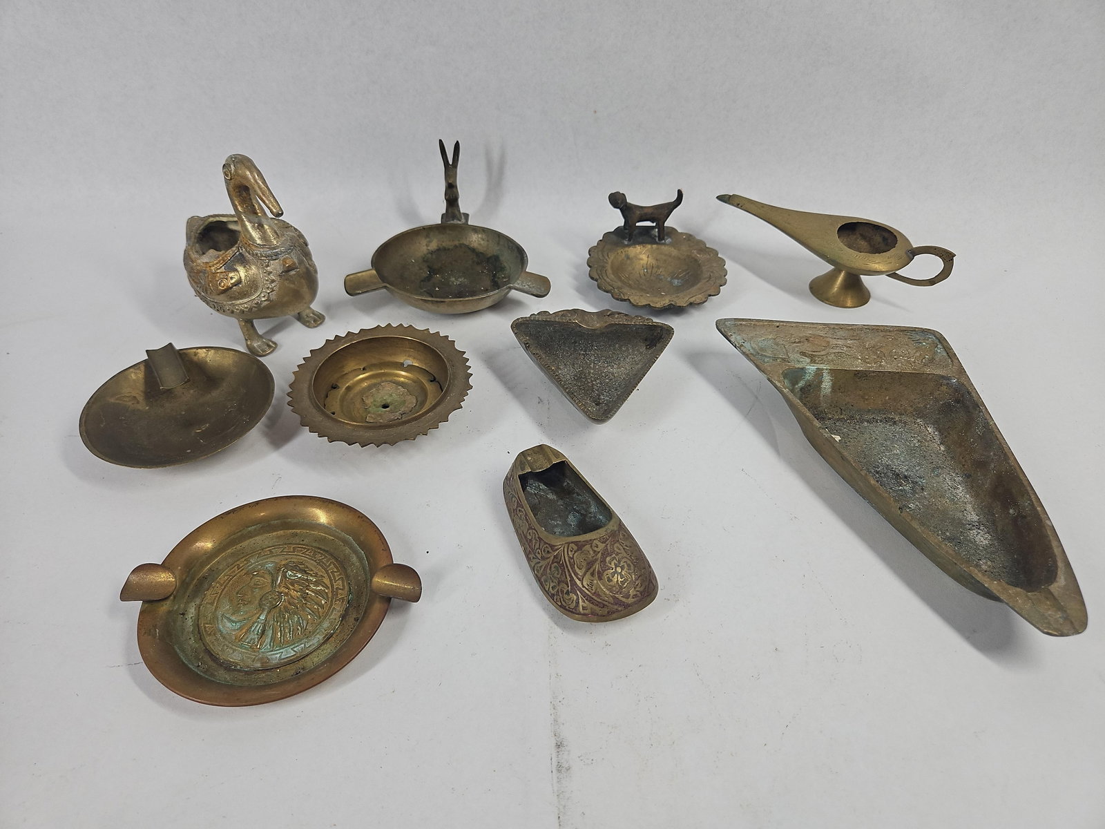 11 Dayagi & Rancho Alegre Brass Items: An assortment of 11 vintage brass decorative objects, primarily comprised of ashtrays and small vessels. The collection features various regional styles and pieces from identifiable makers. A large