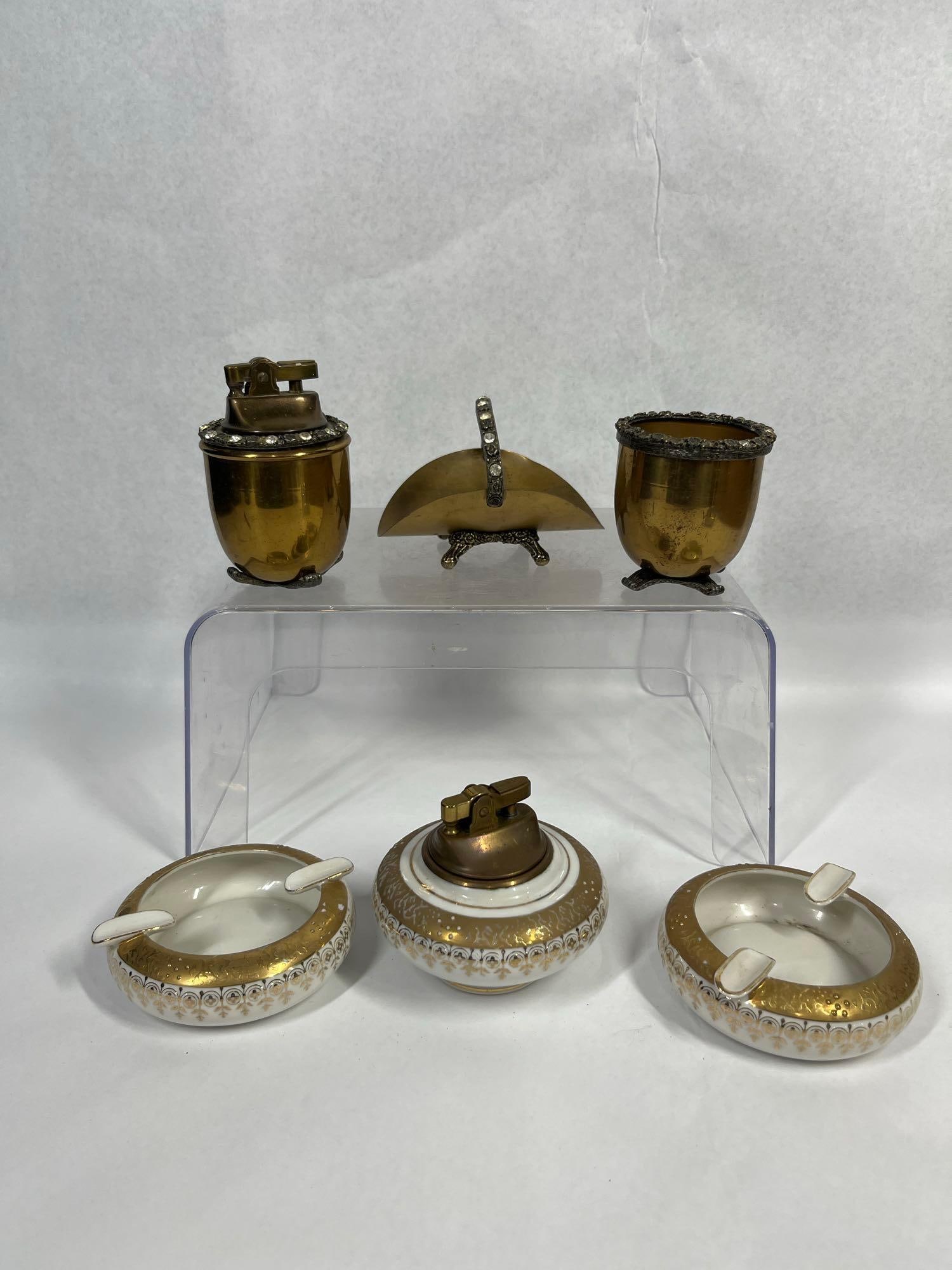Lefton & Jeweled Brass Smoking Set (6): This collection consists of six mid-century table smoking accessories organized into two distinct three-piece sets. The first set is crafted from white porcelain and features hand-painted decoration