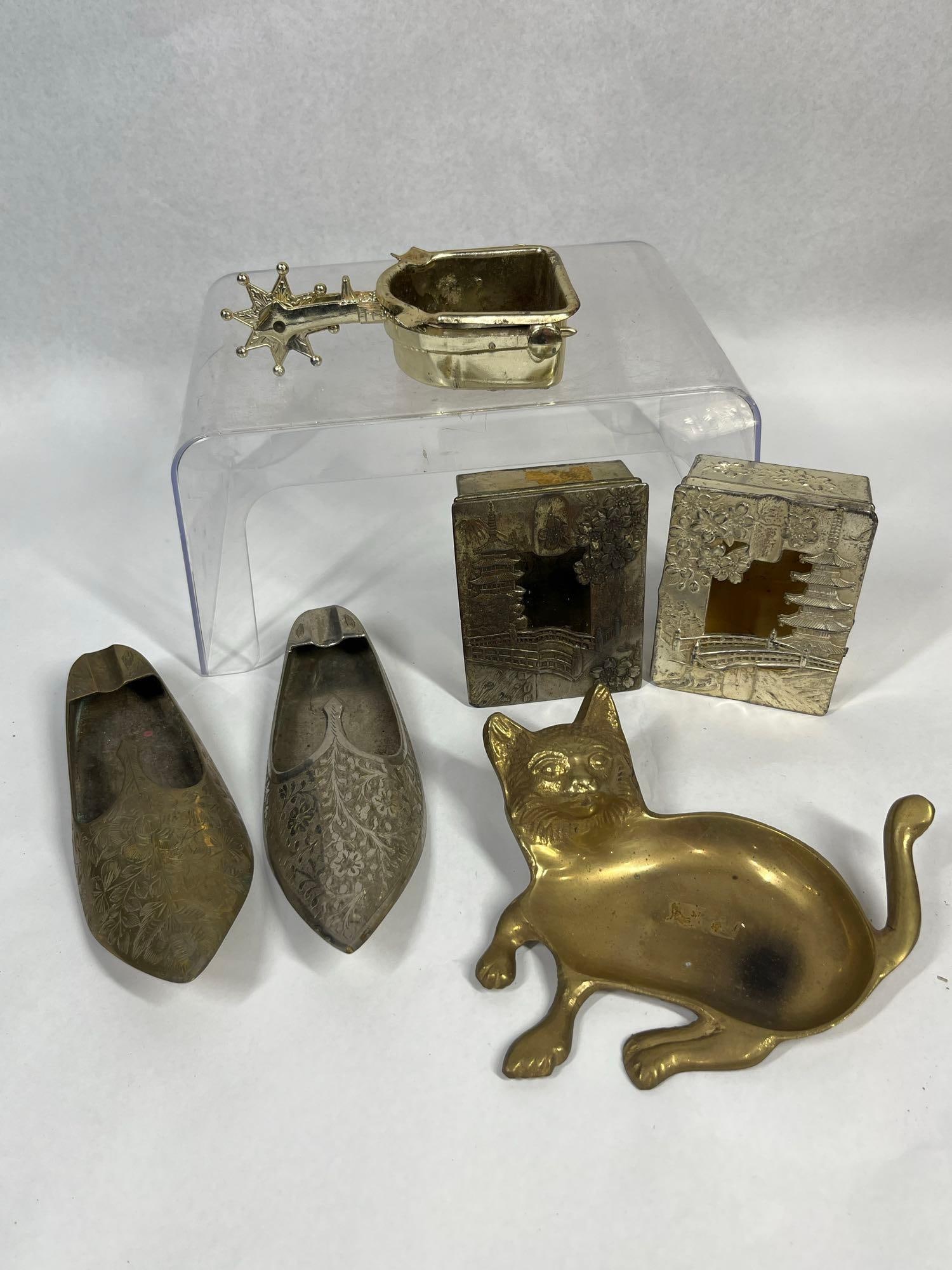 Vtg Metal Ashtrays & Repousse Boxes: An Indian assortment of metal tabletop accessories consisting of novelty ashtrays and lidded boxes. Two slipper-form ashtrays feature engraved floral motifs on the uppers and notched cigarette rests