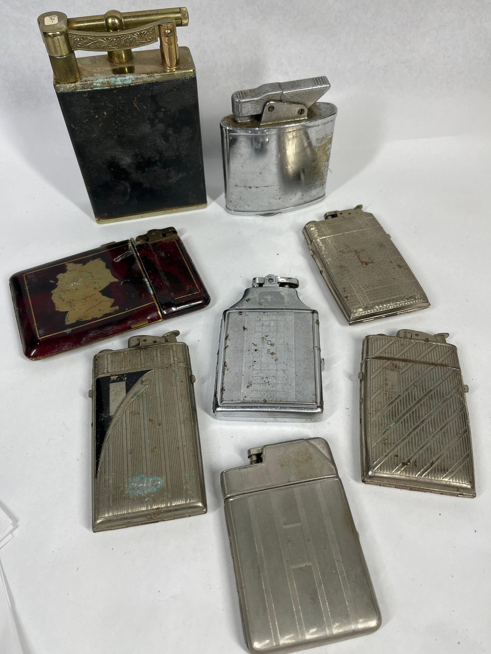 Ronson & Simson Vtg Lighters & Combos: An assortment of vintage lighters and combined cigarette case and lighter units. The group includes a large table lighter featuring a black textured body with brass-tone top components and a curved ch