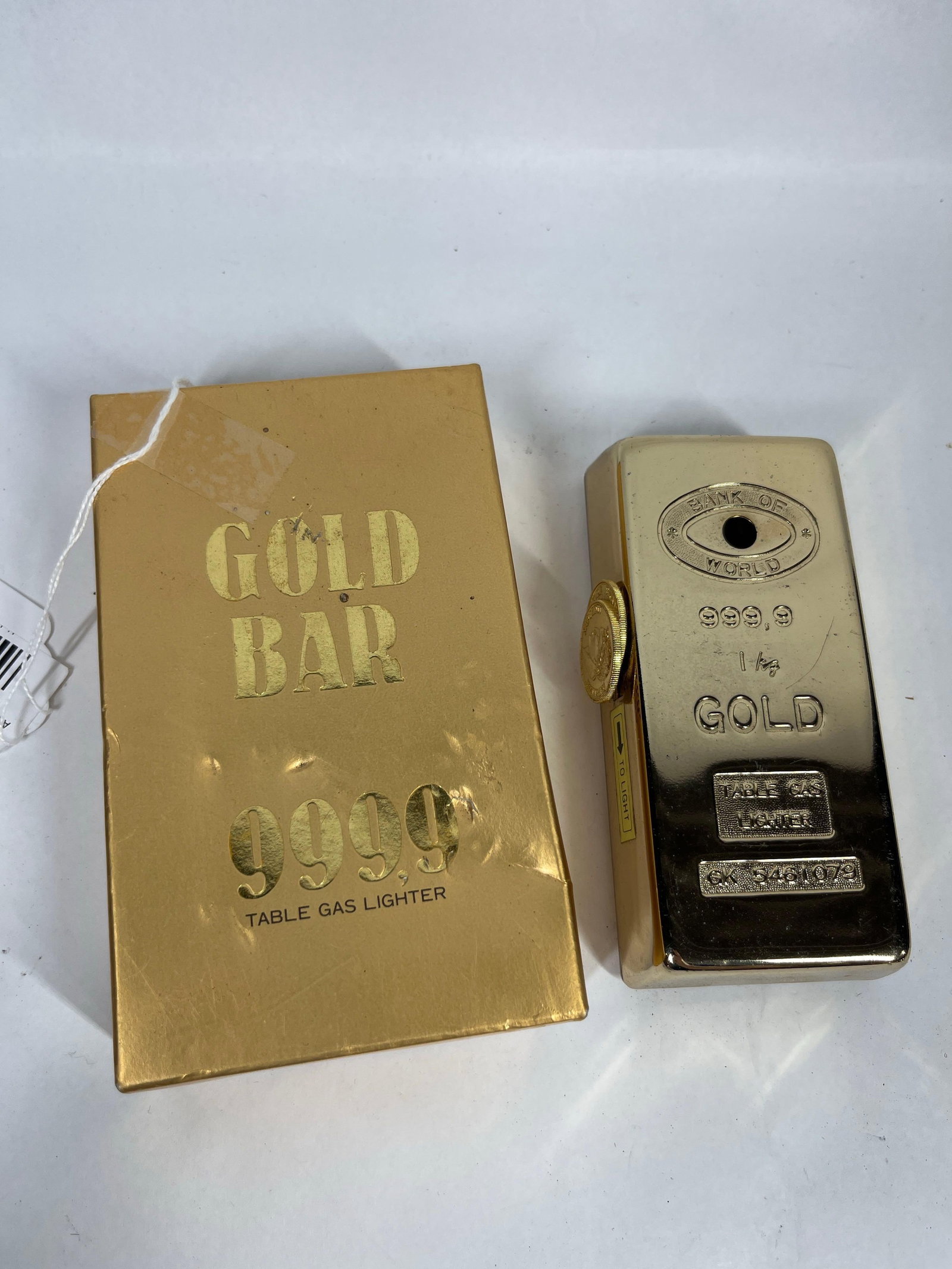 Prince Gold Bar 9999 Gas Lighter w/ Box: A Japanese Prince table gas lighter designed in the form of a 1 kg gold bullion bar. The lighter is constructed with a polished gold-tone metal casing. The top face features an embossed oval logo cont