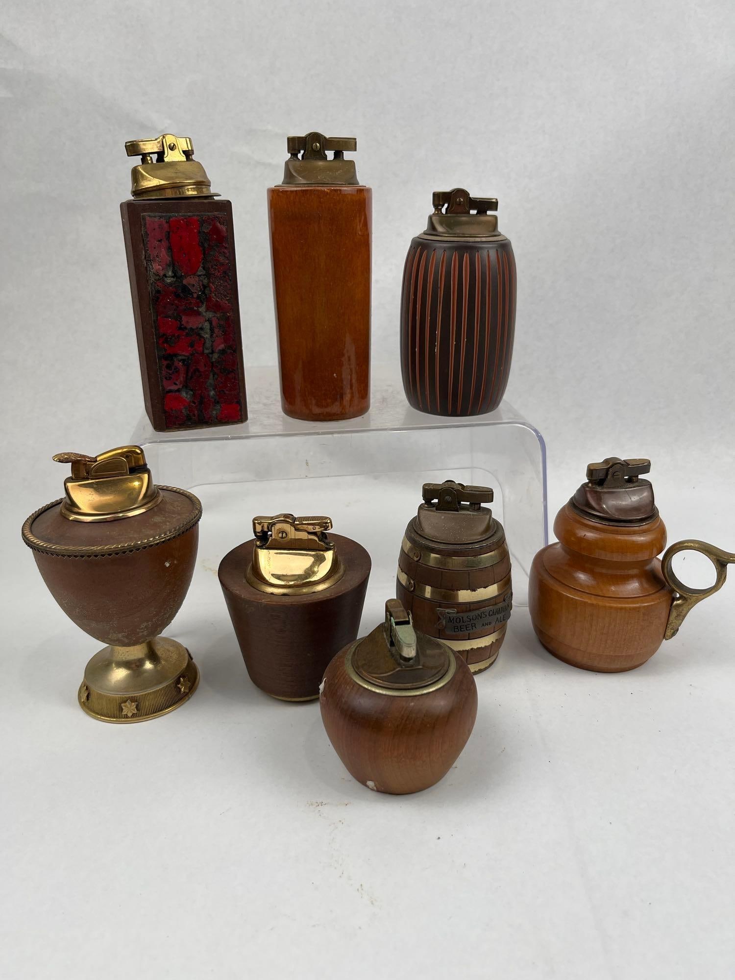 Kenneth Molitor & Molson Table Lighters: A collection of vintage table lighters featuring a diverse assortment of decorative forms in turned wood and ceramic. The group includes a dark brown glazed ceramic lighter with a vertically ribbed