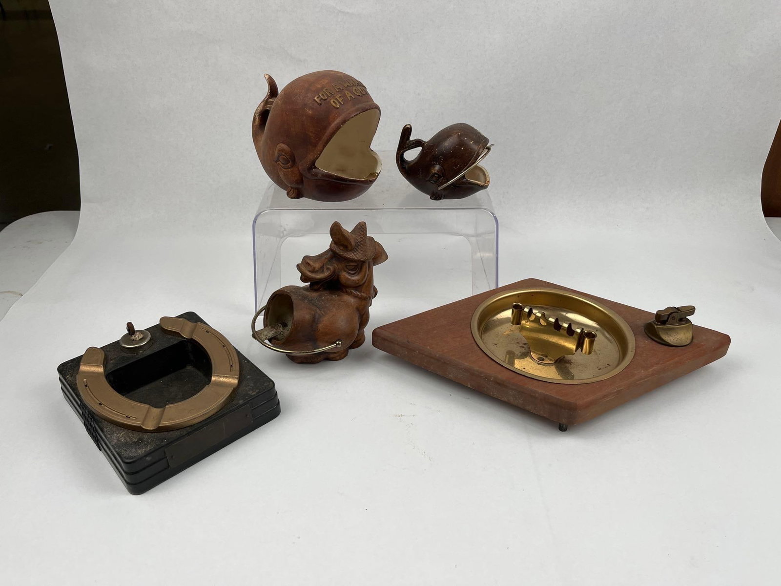 Mid-Century Novelty Ashtrays & Lighters: A group of mid-century smoking accessories featuring novelty ceramic forms and integrated desk lighters. The collection includes two ceramic whale-form ashtrays finished in a dark brown glaze. The