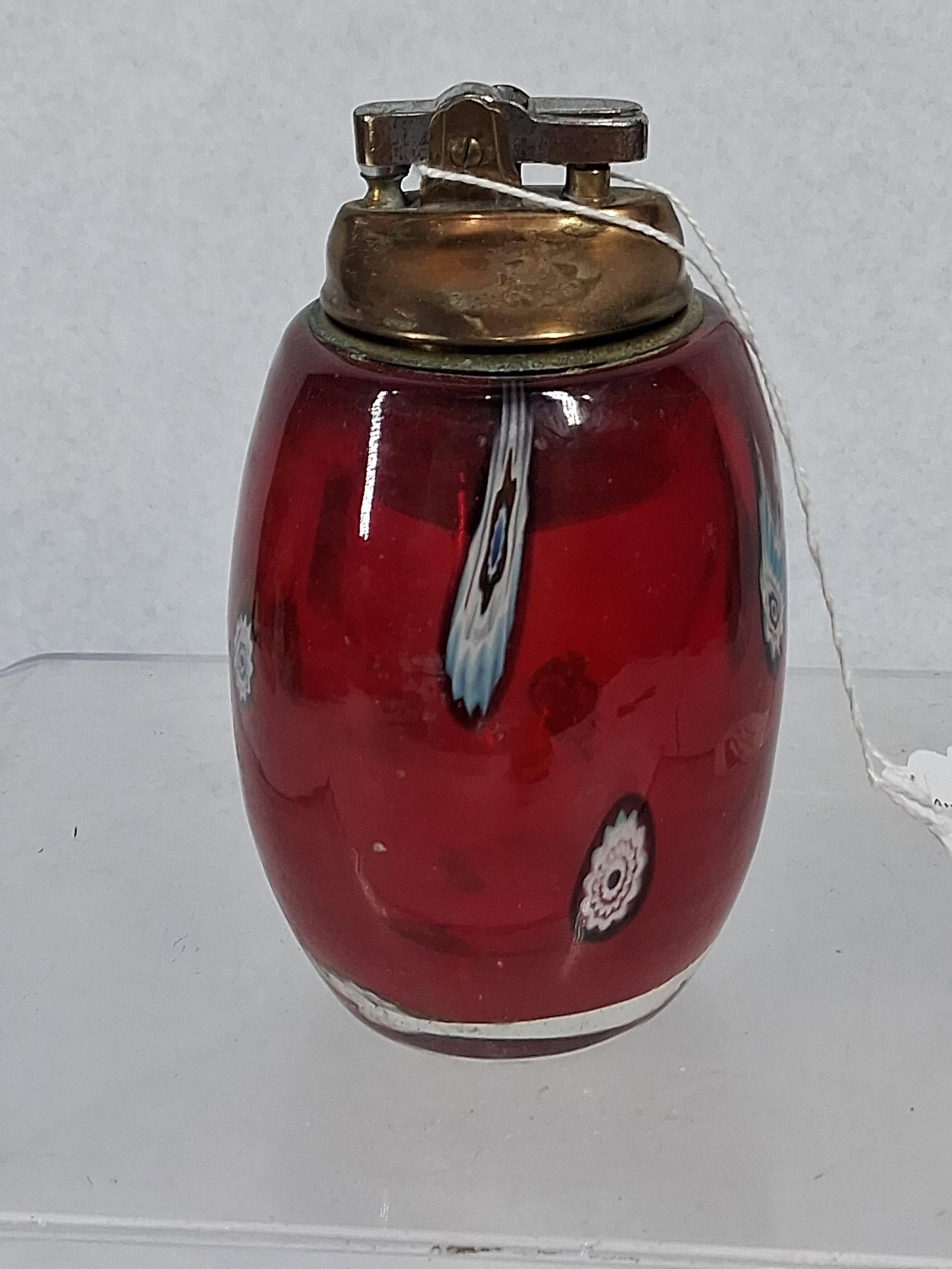 Vtg Red Glass Millefiori Table Lighter: This vintage table lighter is constructed with an egg-shaped, hand-blown glass body in a vibrant red color. The glass features several multi-colored millefiori cane inclusions embedded throughout the