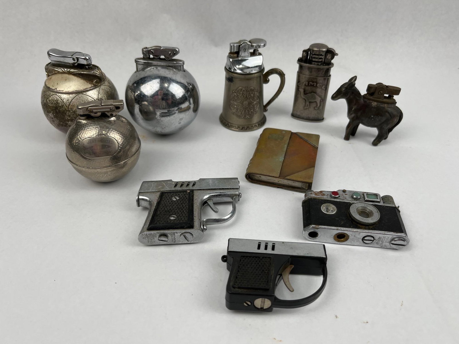 Continental, Cont-Lite Novelty Lighters: A collection of vintage novelty lighters constructed from plated and cast metals in various figural and geometric forms. The group features three spherical table lighters, including one with a