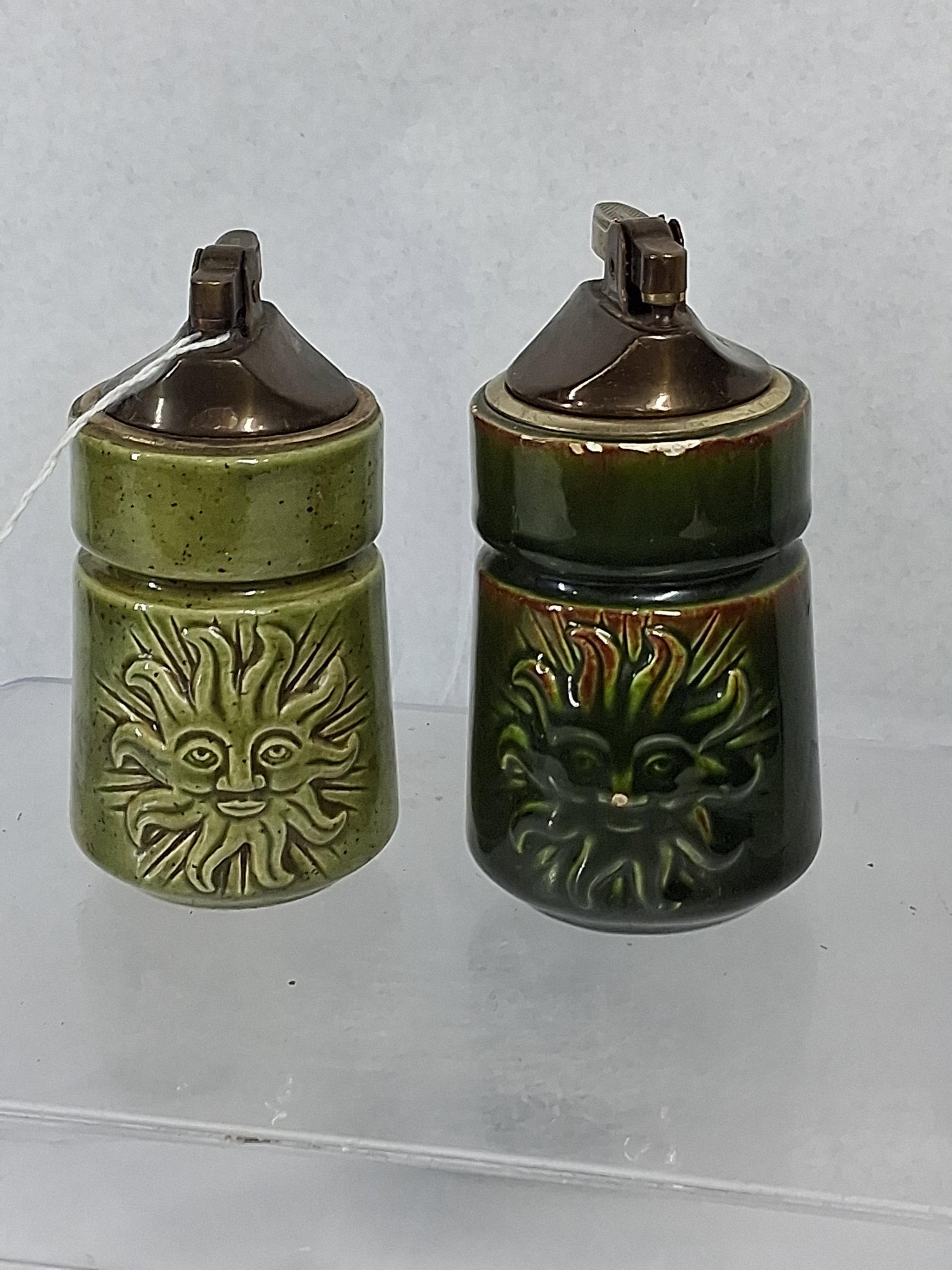 Pair Jeanne B Studio Sun Face Lighters: A pair of studio pottery table lighters featuring Japanese metal inserts and hand-sculpted celestial sun face motifs in high relief. The ceramic vessels are designed in a waisted cylindrical form and 