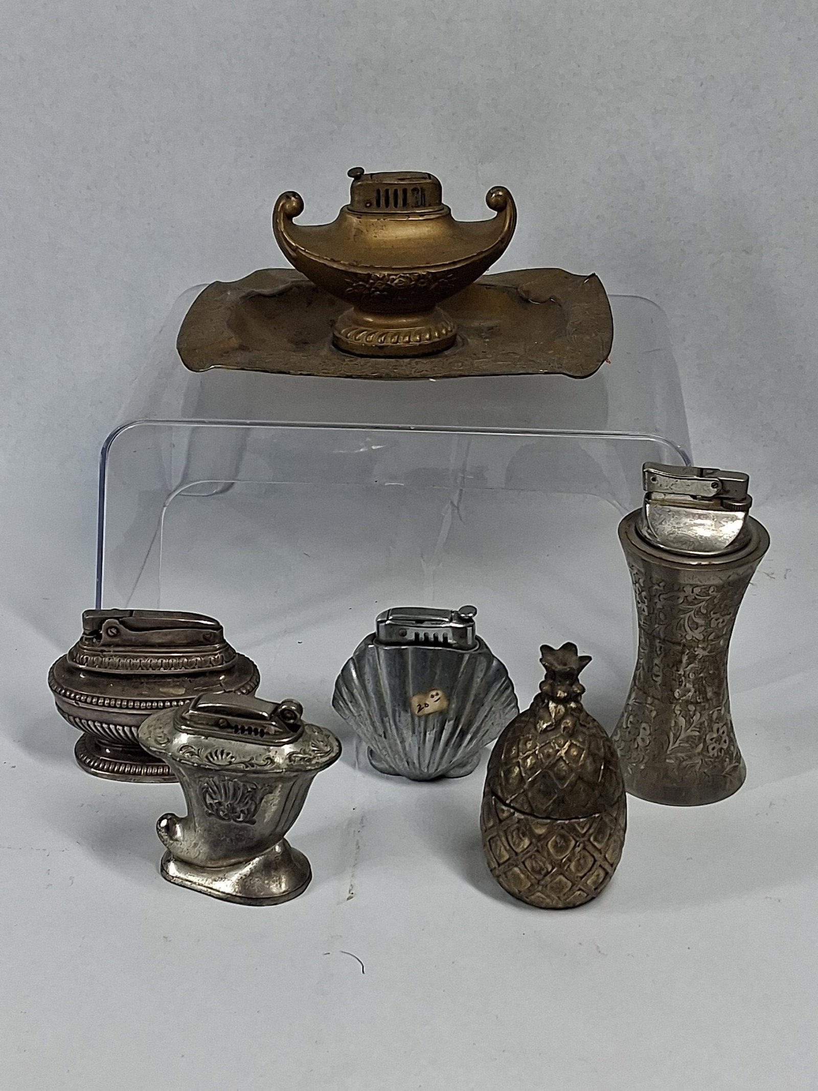 Ronson & Continental Vtg Table Lighters: A collection of various figural and novelty table lighters along with a decorative pineapple-shaped box. The group features a brass-toned lighter in the form of an Aladdin lamp resting on a matching