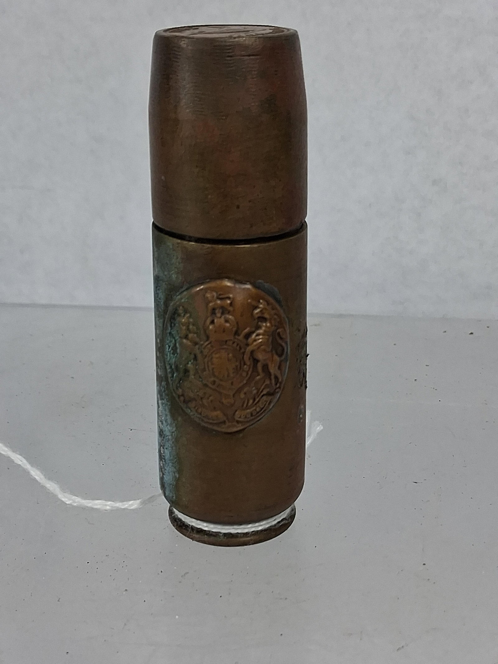 British 1942 Trench Art Shell Lighter: This handmade trench art petrol lighter is constructed from a brass 20mm cannon shell casing and features a removable slip-fit cap. The front of the body is decorated with an applied brass badge