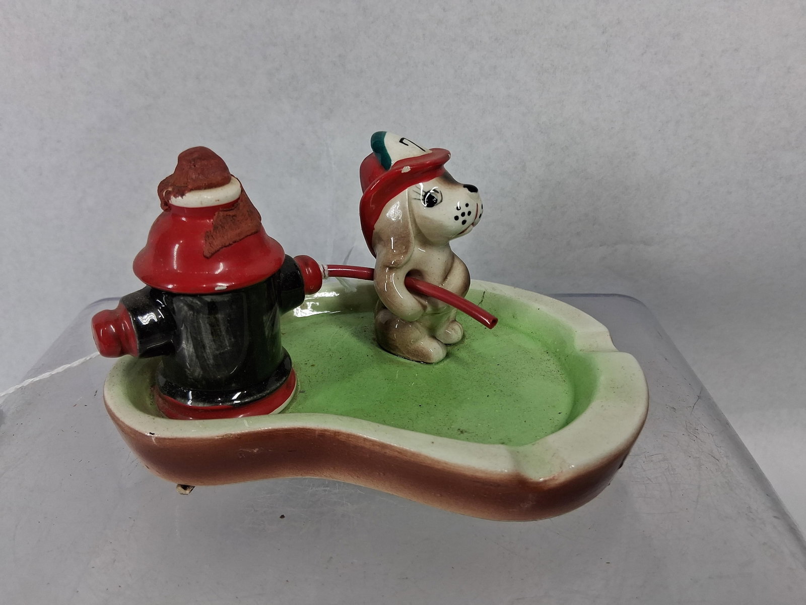 Tilso Japan Firefighter Puppy Ashtray: A Japanese hand-painted ceramic novelty ashtray featuring a firefighter theme. The piece consists of a stylized brown-and-white puppy wearing a red fire helmet with a black numeral 7, positioned