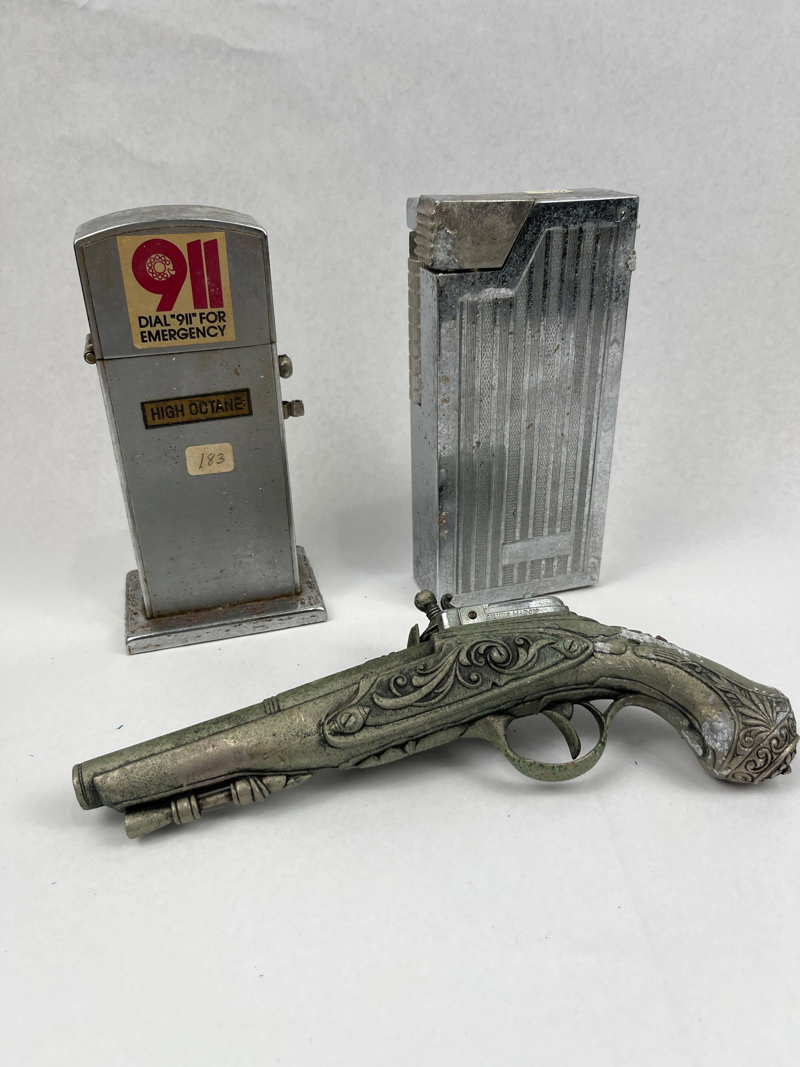 Trio Vtg Flintlock & Gas Pump Lighters: This collection consists of three vintage novelty table lighters manufactured in Japan and by Silver Match. The first lighter is shaped like a classic gas pump, constructed from chrome-plated metal. I