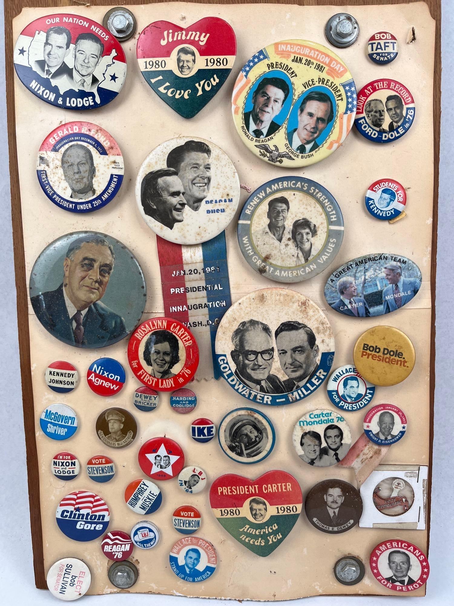 US Presidential Buttons & Memorabilia: A collection of approximately 40 United States political campaign buttons and items of ephemera, spanning from the late 1920s through the early 1990s. The assortment is mounted to a plain wooden displ