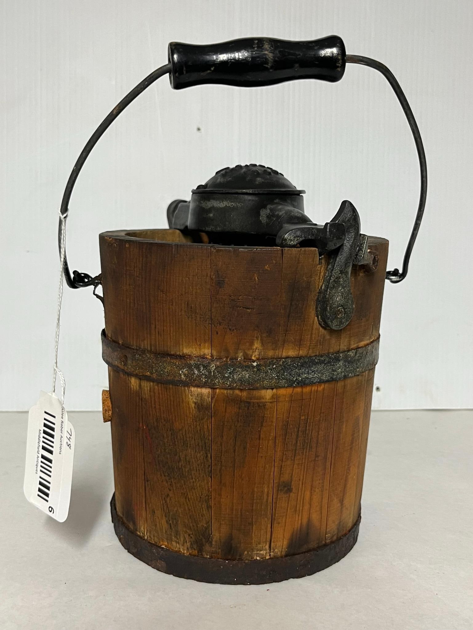 Arctic Wooden Ice Cream Freezer 1889: This hand-crank ice cream freezer features a bucket of wooden stave construction bound by three oxidized metal hoops. The gear mechanism and lid are made of cast iron, and the device includes a metal 