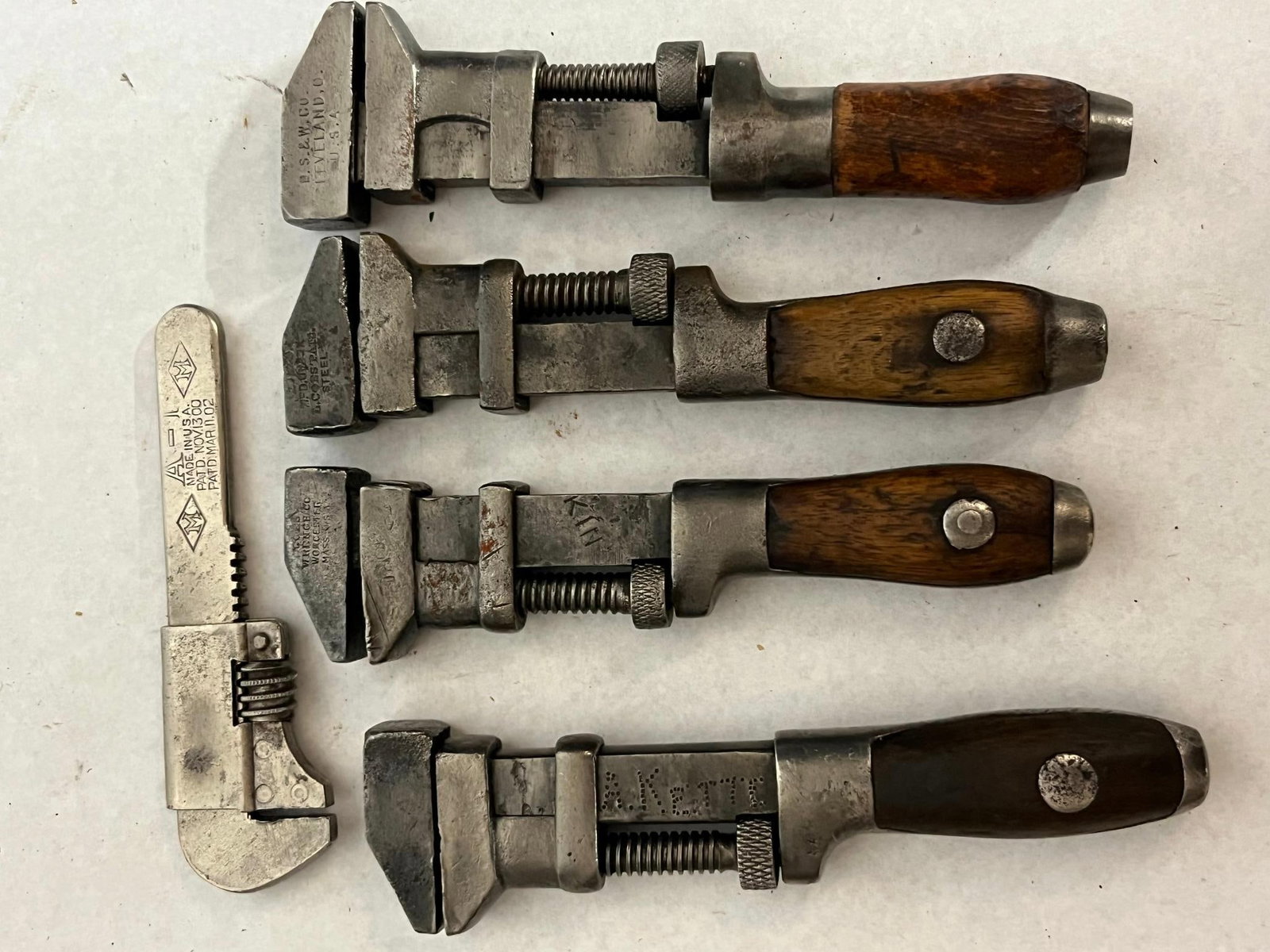 5 Antique Steel & Wood Handled Wrenches: A collection of five American adjustable wrenches dating from the late 19th to early 20th century. The first wrench features two-piece wooden handle scales and a steel body with an impressed mark on