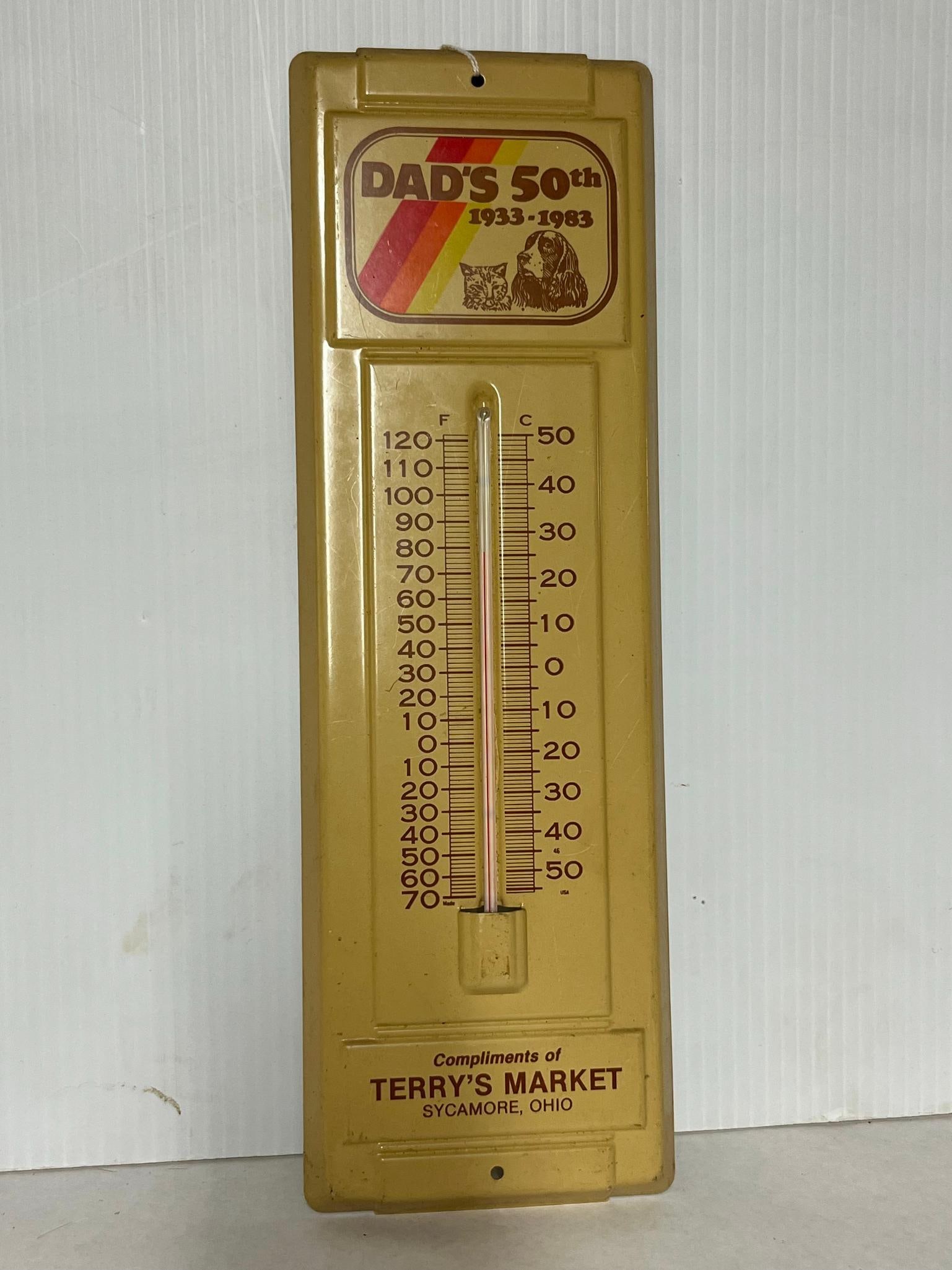 Terry's Market Ohio Thermometer 1933-83: A American advertising thermometer featuring a painted yellow-tan tin housing. The top portion of the thermometer displays a lithographed graphic with a red, orange, and yellow diagonal striped