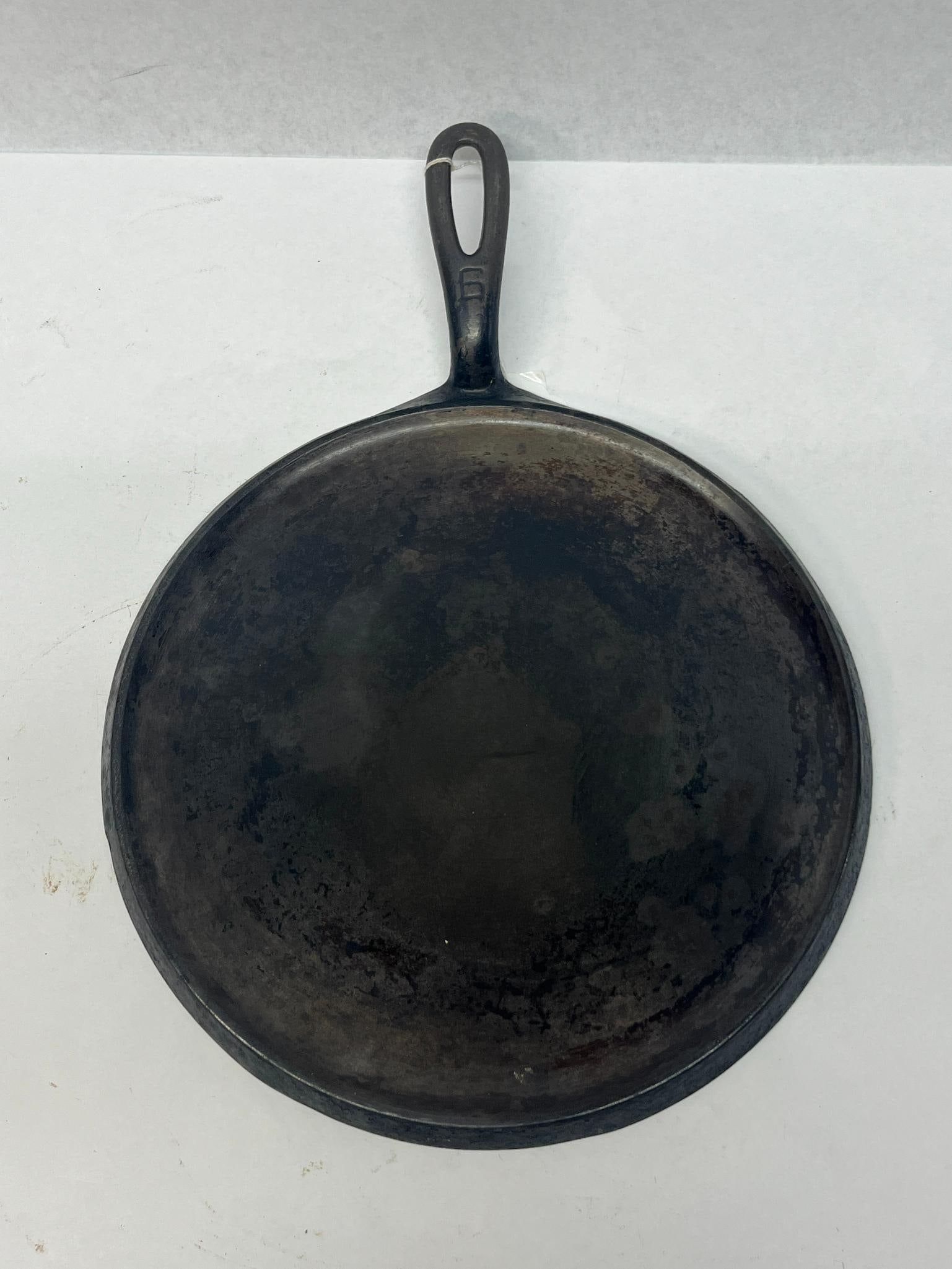 Griswold No. 8 Round Cast Iron Griddle: An American round cast iron griddle featuring a shallow rimmed cooking surface and an integral tapered handle with a teardrop-shaped hanging hole. follow the upper perimeter; the number 8, the