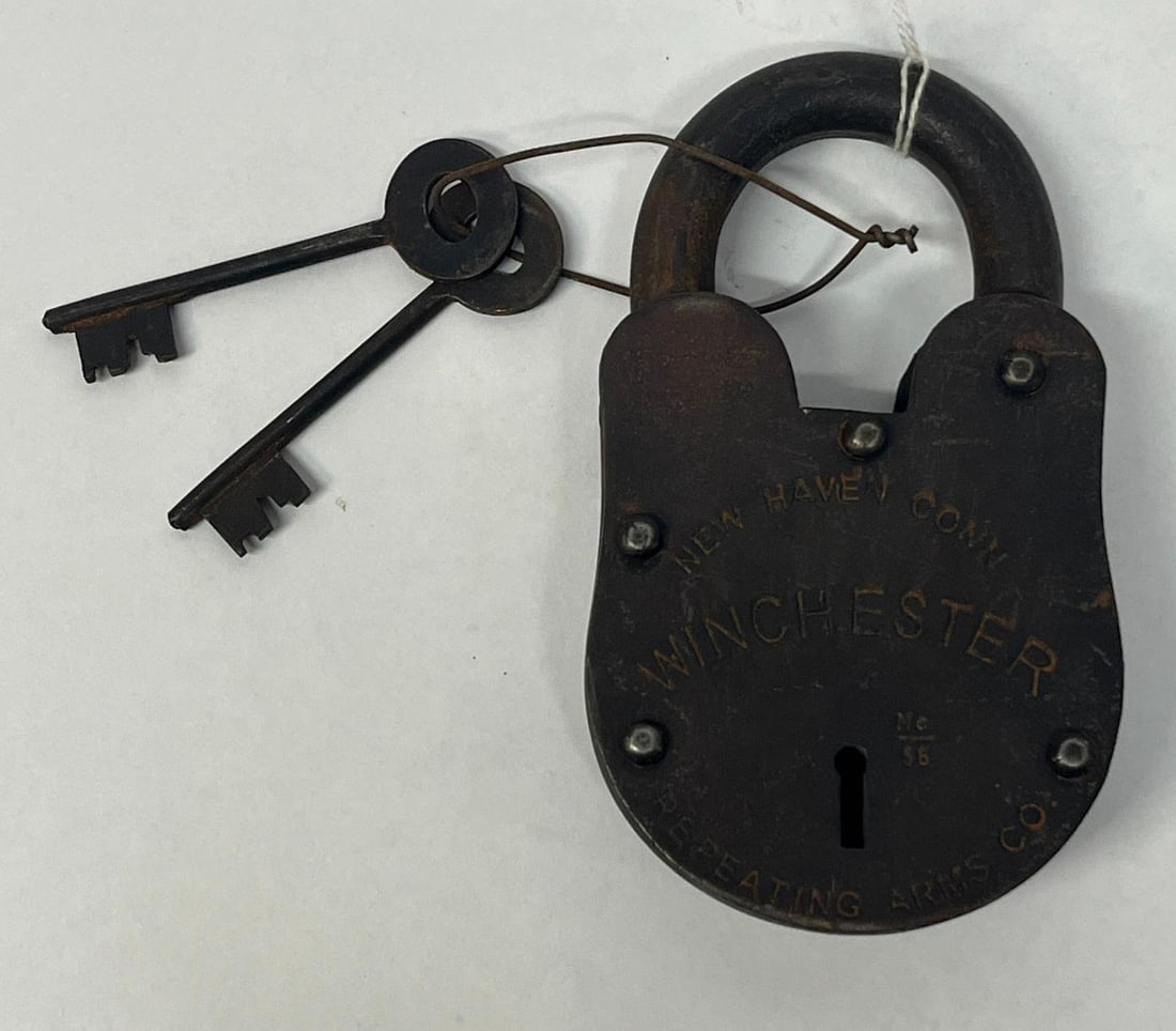Winchester Repeating Arms Iron Padlock: A wrought iron lever-tumbler pancake style padlock manufactured in the United States. The designation No 56 is stamped just above the keyhole. The reverse face bears an impressed arc reading OLIVER F 