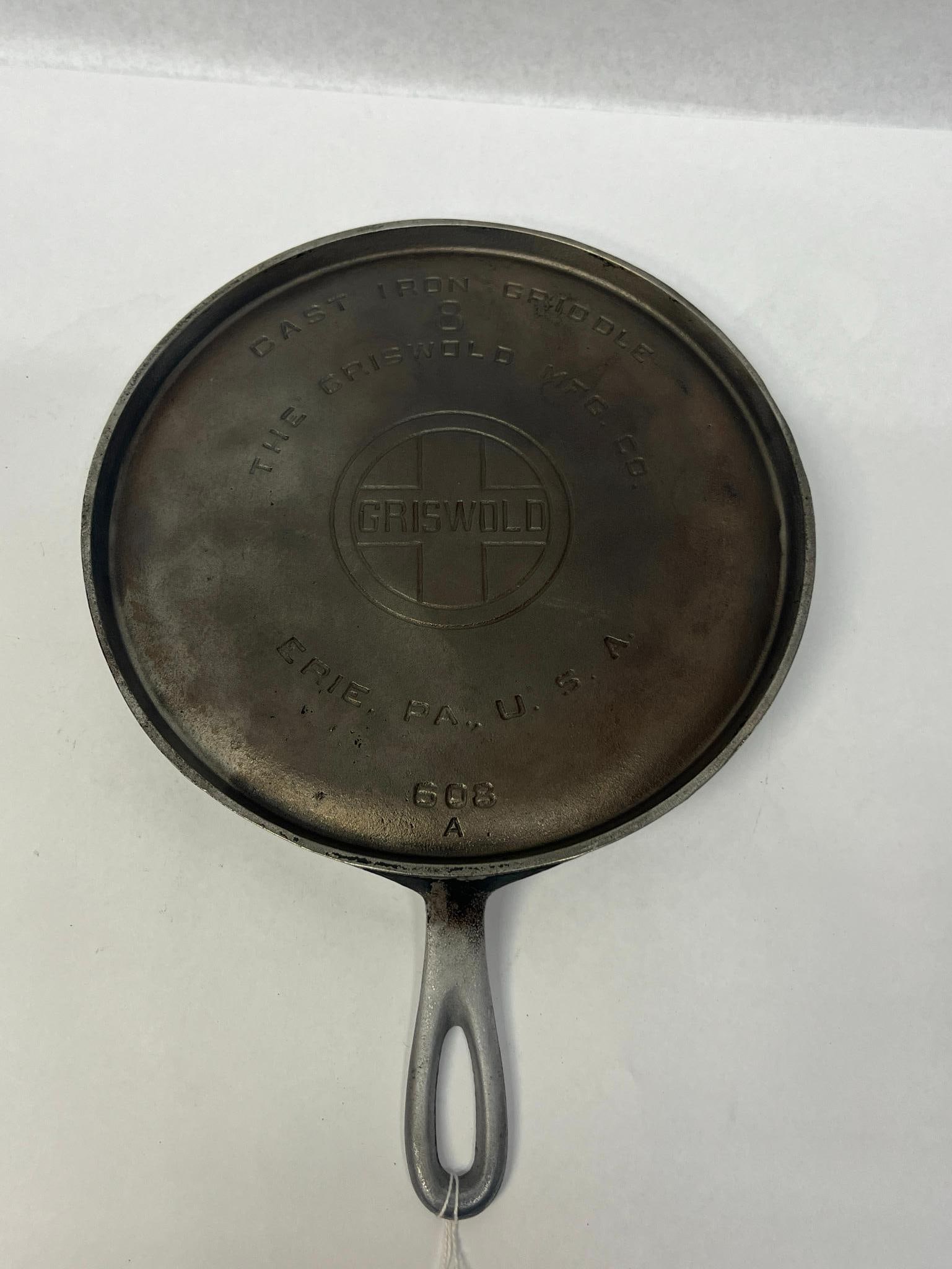 Griswold No. 8 Plated Cast Iron Griddle: A round American cast iron griddle featuring a metallic plated finish. At the top, the words CAST IRON GRIDDLE are impressed above a size number 8. arched over a circular logo containing a cross with