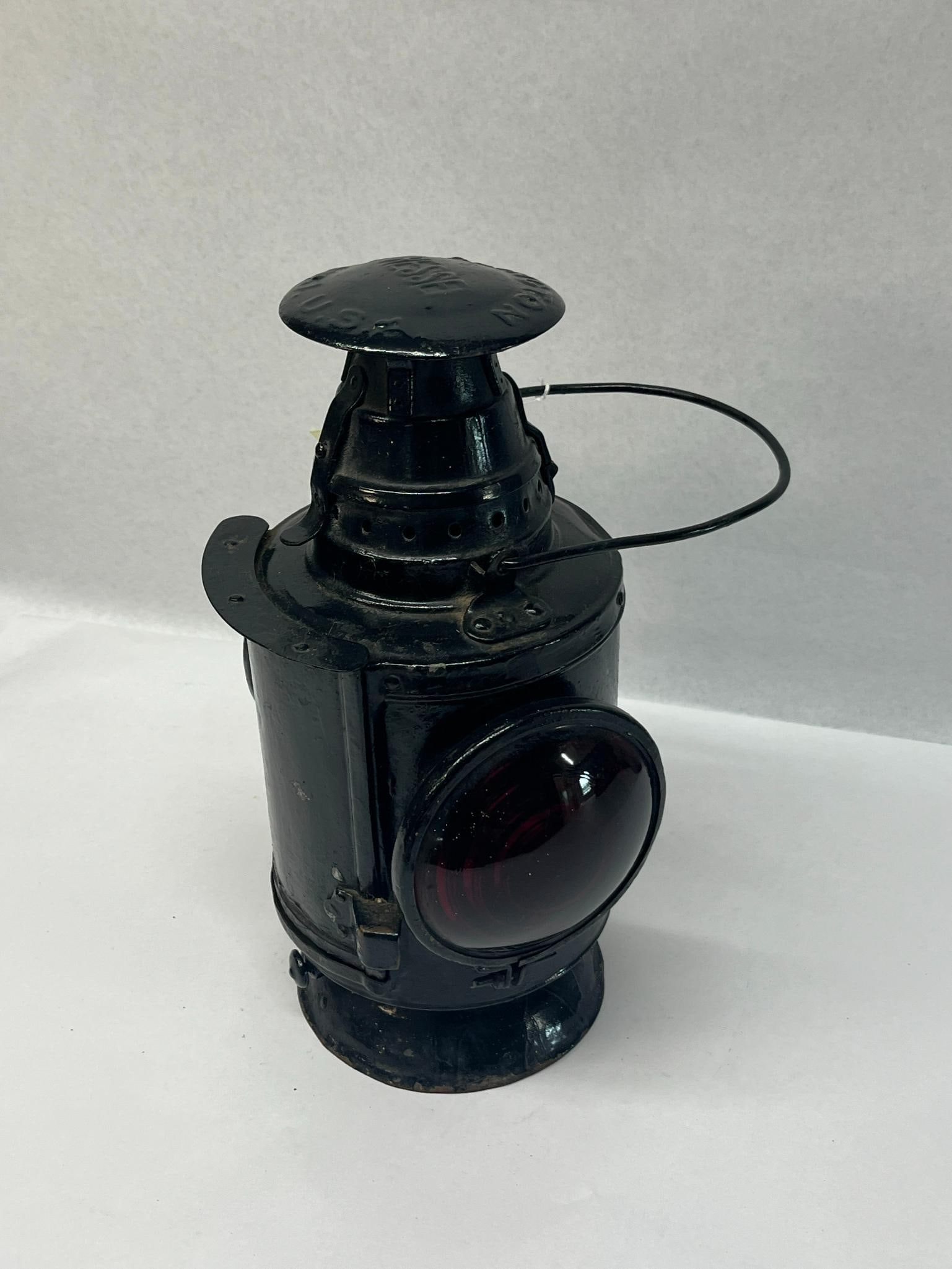 Dressel Three-Way Railroad Lantern: An American railroad signal lantern produced by the Dressel Railway Lamp and Signal Company. The piece is constructed from black painted metal and features a cylindrical body, a tiered chimney, and a