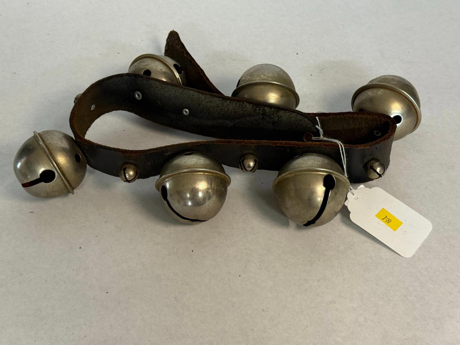 Antique American Sleigh Bells, Leather: A set of six large and four small nickel-plated metal sleigh bells mounted on a dark brown leather strap, dating from the late 19th to early 20th century. Strap length is approximately 15 to 18