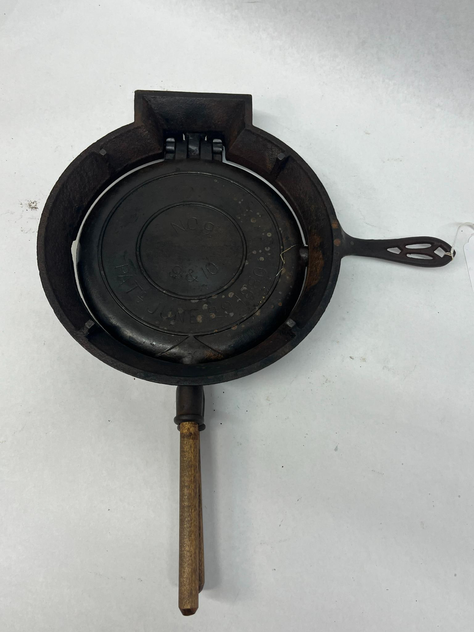 Griswold American No 9 Waffle Iron: A late 19th-century cast iron waffle iron produced by the Griswold Manufacturing Company. An impressed mark on the exterior of the top paddle is readable as GRISWOLD MFG CO ERIE PA around a central