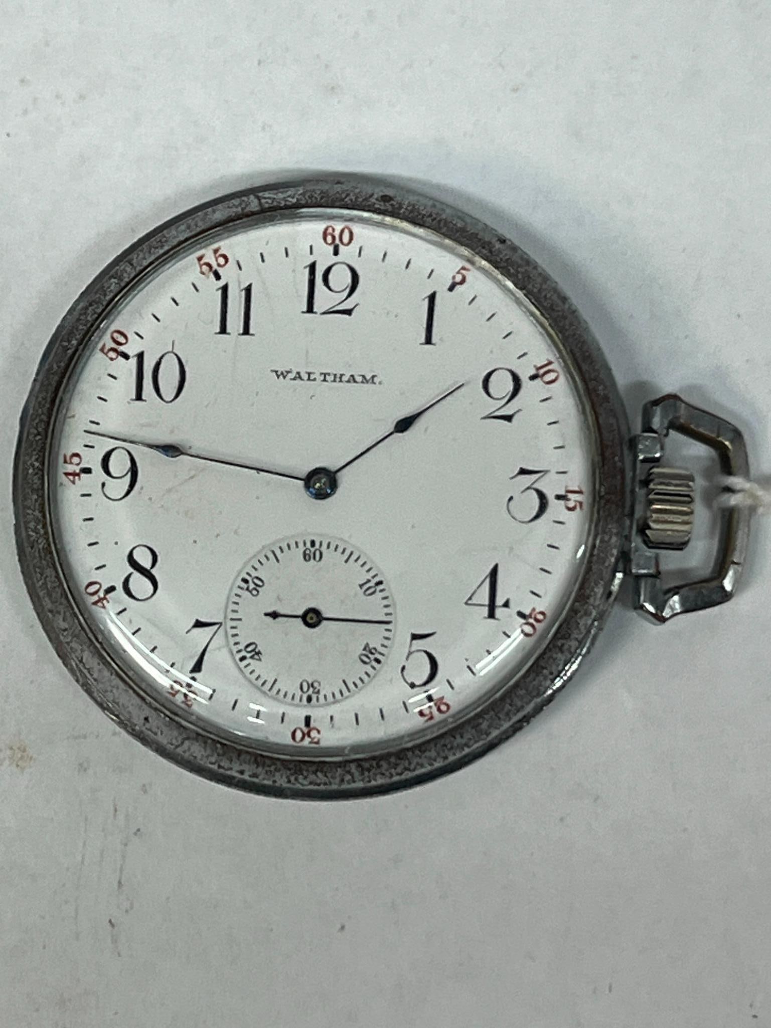 Waltham 15 Jewel Open Face Pocket Watch: An open face mechanical pocket watch featuring a white enamel dial with black Arabic numerals for the hours and an outer track of red Arabic numerals marking five-minute intervals. The hands are