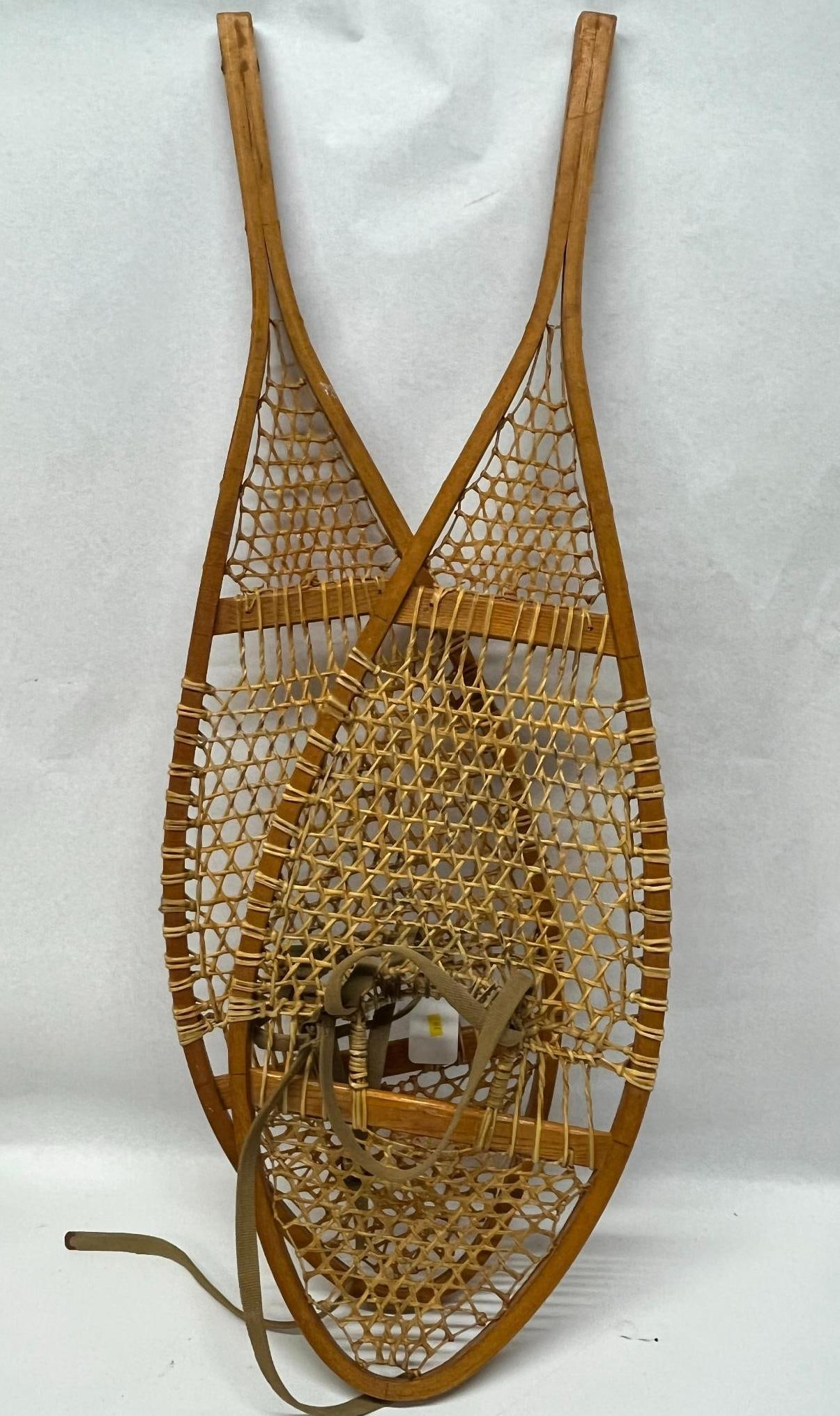 Pair Bentwood & Rawhide Snowshoes: A pair of traditional teardrop-shaped snowshoes featuring bentwood frames and hand-woven rawhide decking. The bindings are constructed from olive drab canvas and nylon webbing straps with adjustable