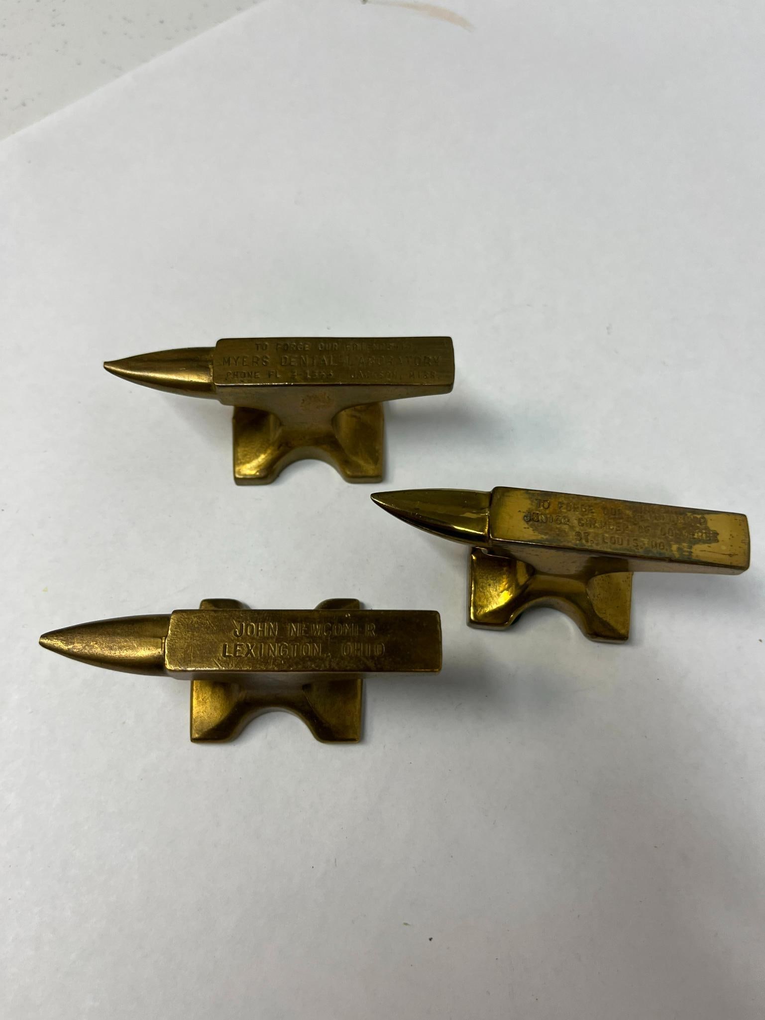 3 Myers & JCC Advertising Brass Anvils: A collection of three promotional miniature anvils cast in solid brass. The first anvil features impressed lettering on its top surface that reads TO FORGE OUR FRIENDSHIP MYERS DENTAL LABORATORY