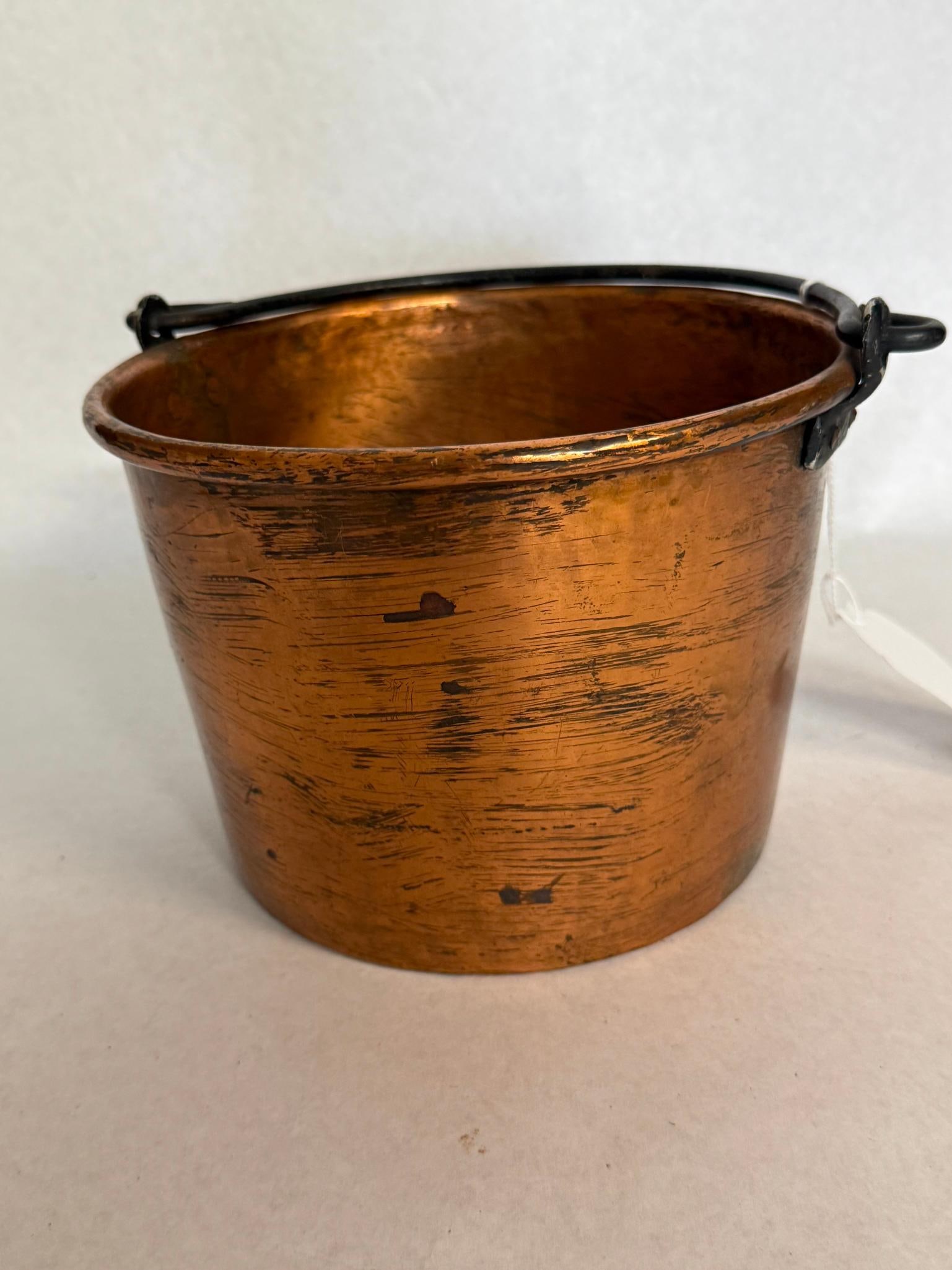 Sprague Mfg. Co. Bucyrus Copper Bucket: An antique American copper utility bucket featuring a tapered cylindrical body and a rolled top rim. The item is constructed from sheet copper with a separate base joined to the body. The underside