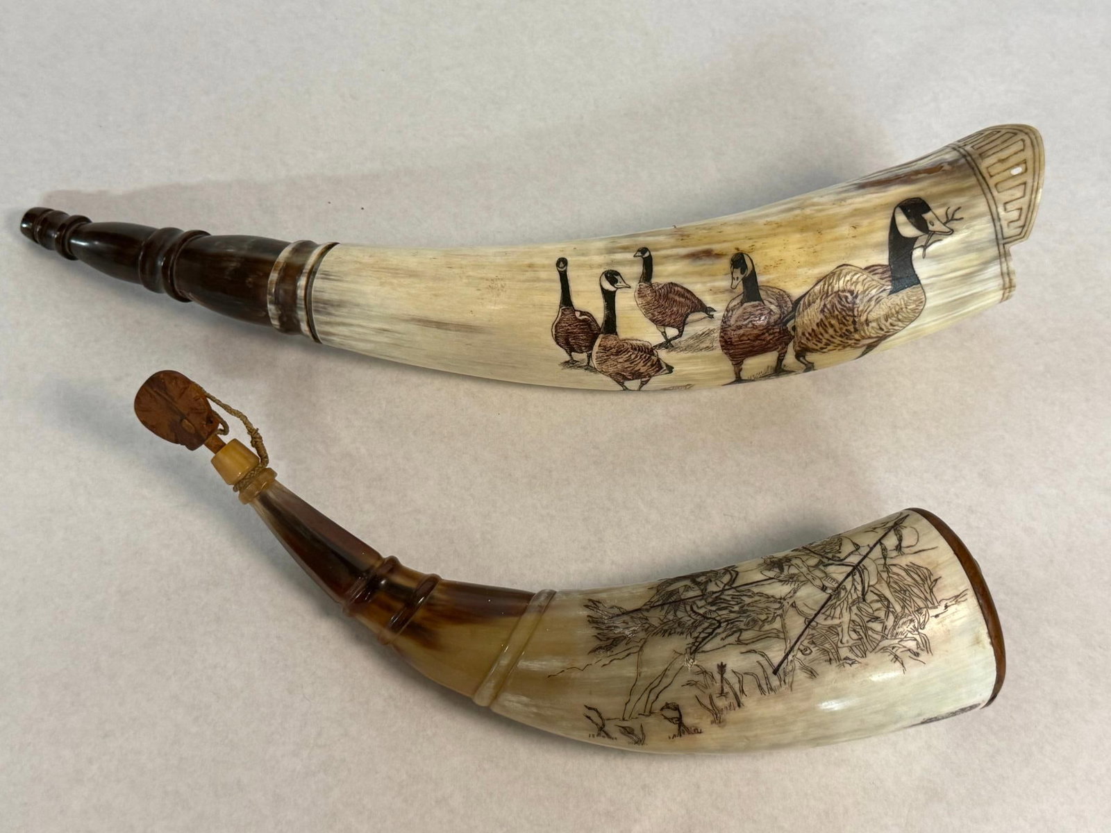 Niko Scrimshaw Powder Horns 1997 & 1999: This lot consists of two contemporary hand-crafted powder horns featuring decorative scrimshaw work, constructed using traditional methods for the black powder or historical reenactment market. Near