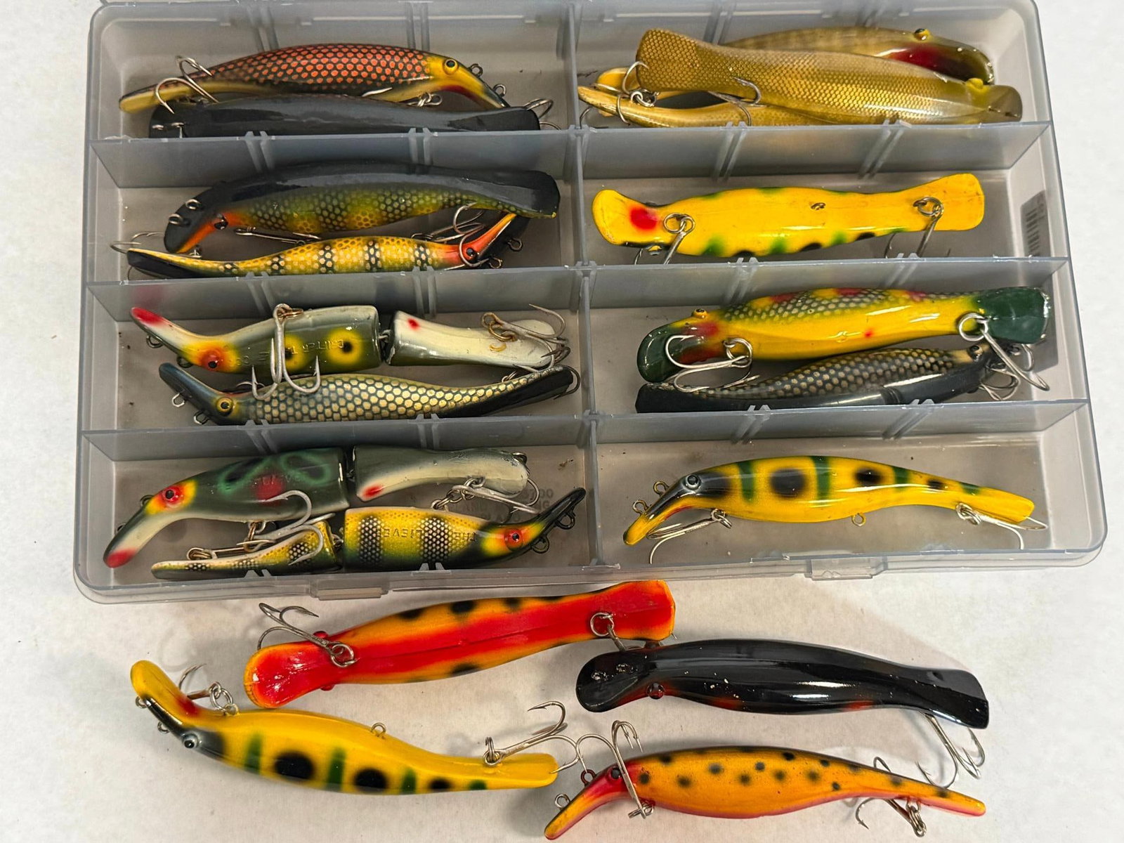 19 Drifter Tackle Musky Fishing Lures: This lot comprises a collection of approximately 19 hard-body fishing lures designed for large predatory fish such as musky and northern pike, contained within a clear plastic multi-compartment