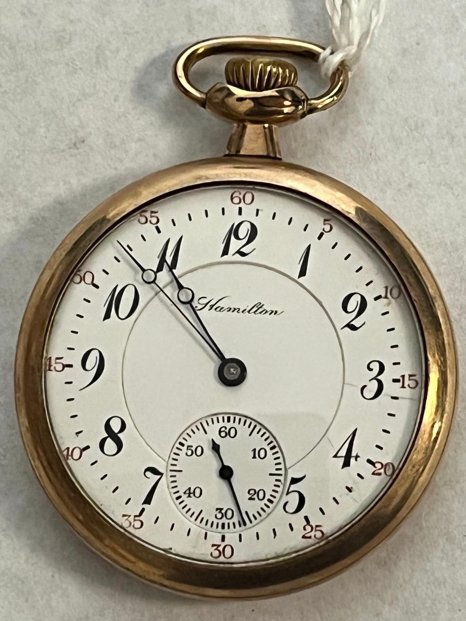 Hamilton 974 17 Jewel Open Face Watch: A Hamilton Grade 974 open-face pocket watch featuring a white porcelain enamel double-sunk dial. Time is indicated by a blued steel spade-and-whip hand set. The watch is powered by a manual-wind