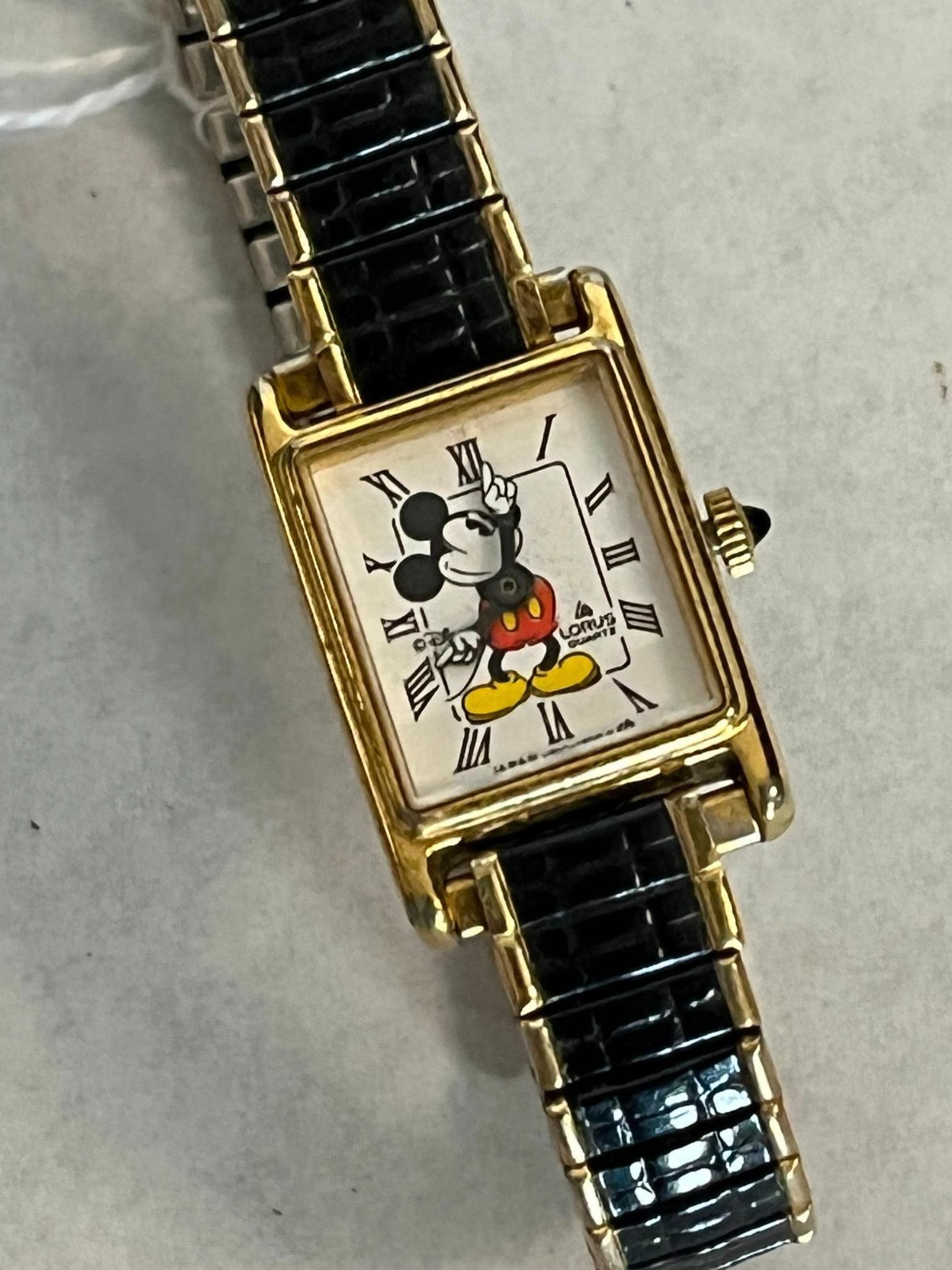 Lorus Mickey Mouse Tank Watch V810-5000: A Japanese quartz wristwatch by Lorus featuring a Disney Mickey Mouse character theme. The stainless steel case back is stamped with the text BASE METAL BEZEL, STAINLESS STEEL BACK, and the reference