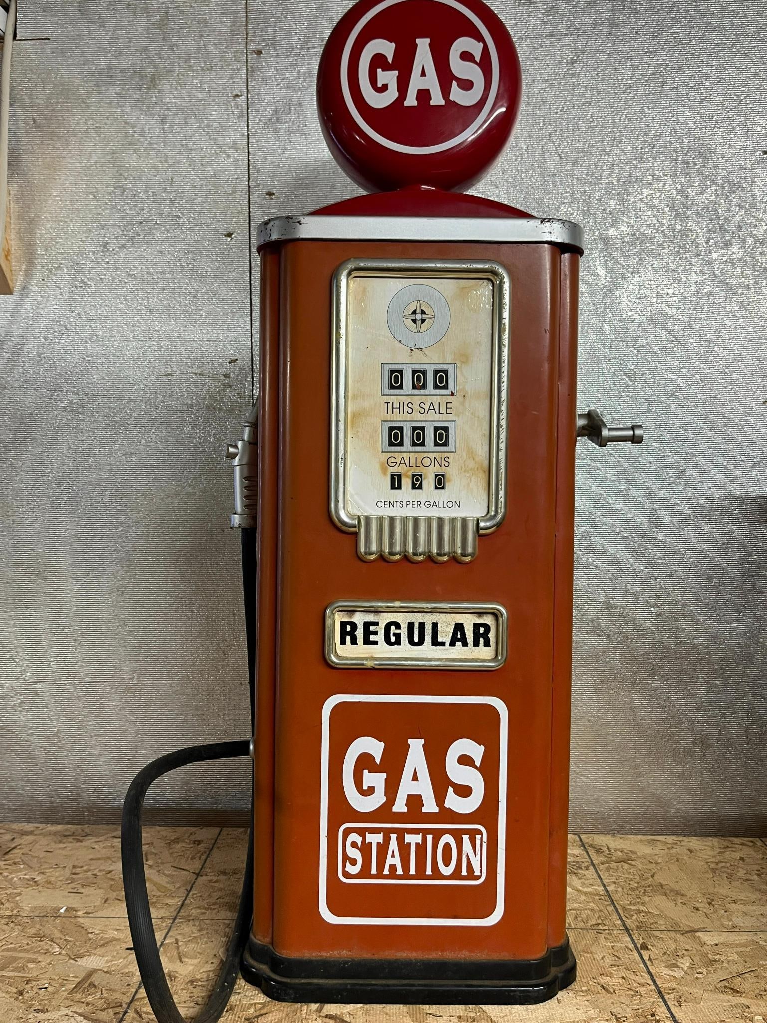 Red Gas Pump Cabinet: A floor-standing decorative gas pump cabinet designed in the style of mid-20th-century petroliana. The main faceplate is cream-colored and displays three mechanical-style rolling counters with text
