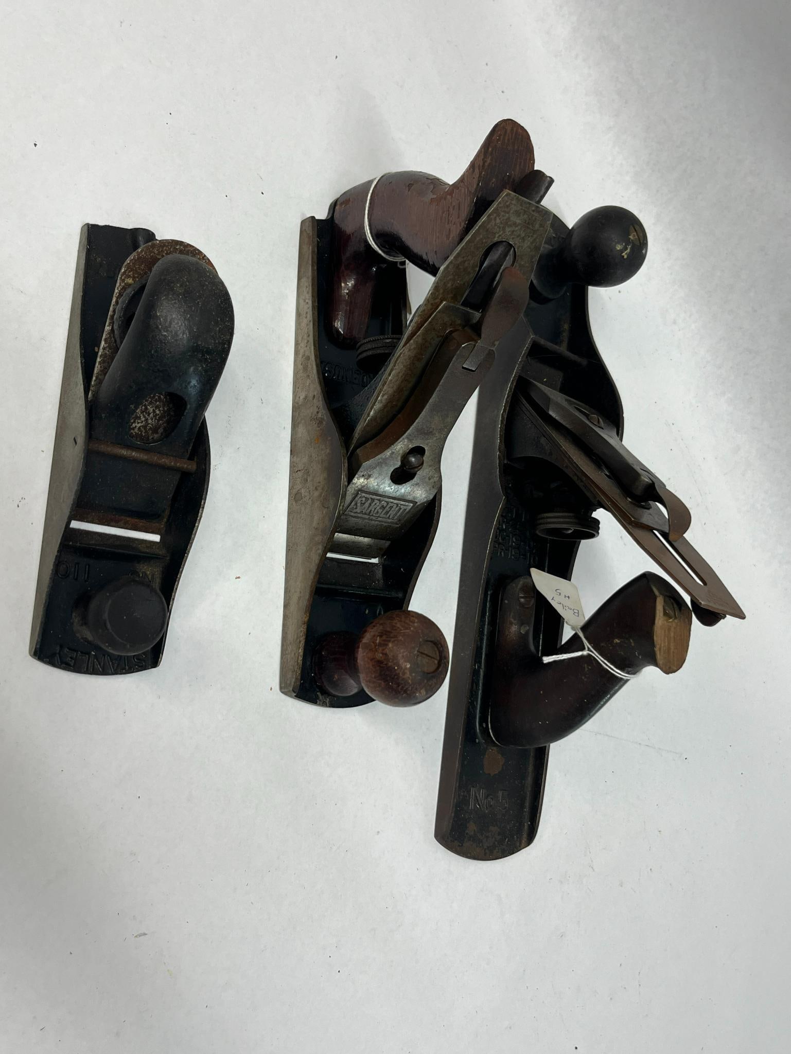 3 Stanley & Sargent Antique Hand Planes: This set comprises three American woodworking hand planes constructed from cast iron with steel components and wooden grips. The first tool is a bench plane with a bed marked No 5 at the rear (photo