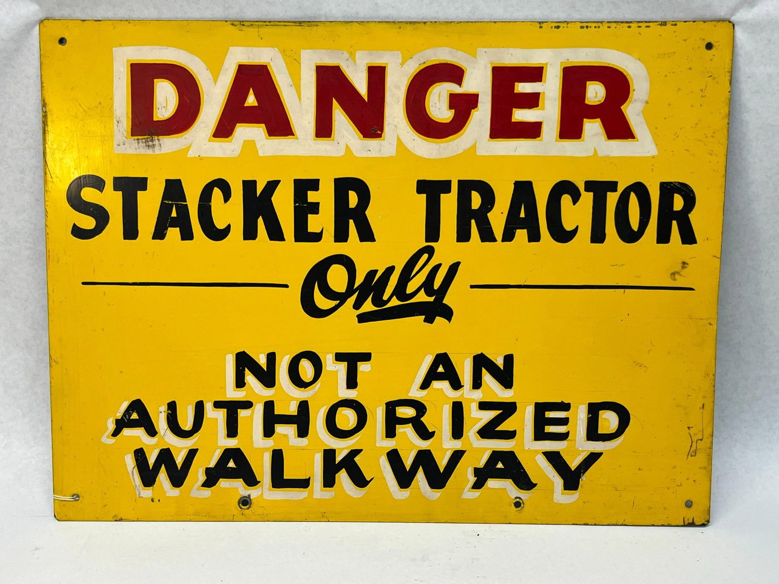 Hand-Painted Stacker Tractor Sign: This is a mid-century industrial safety sign constructed from painted sheet metal. The sign features a bright yellow background with hand-painted text in three distinct sections. The middle section