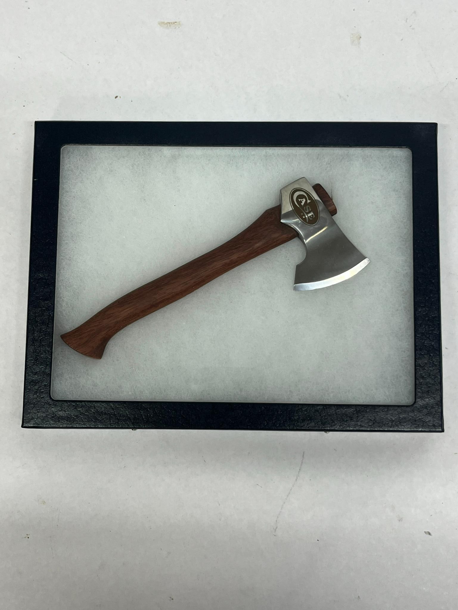 Case XX Mini Camp Hatchet in Shadowbox: A small camp hatchet featuring a polished steel head and a contoured hardwood handle. The side of the hatchet head displays a laser-etched oval mark containing the name CASE positioned above two