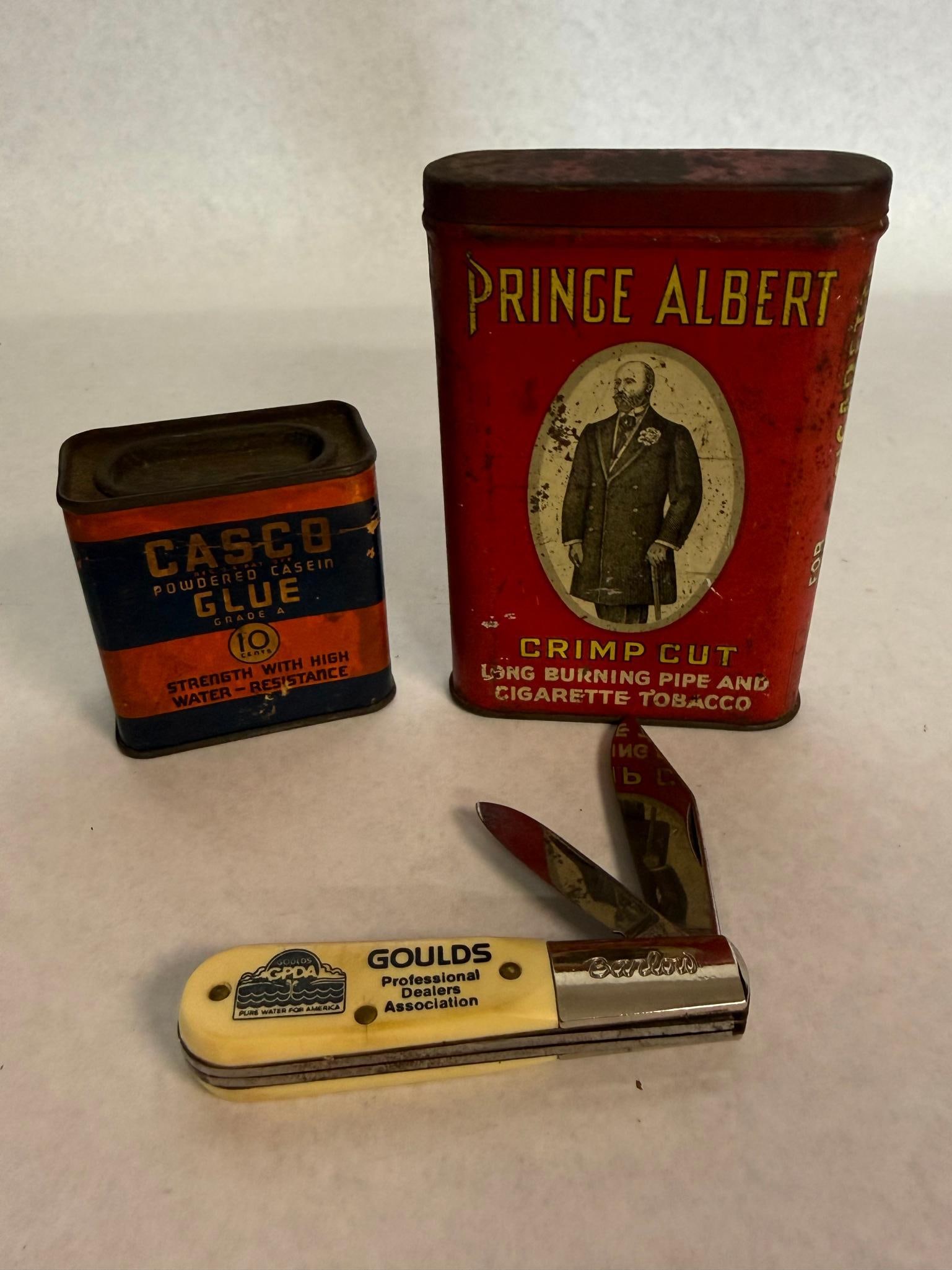 Colonial Barlow Knife & 2 Litho Tins: This lot contains a selection of utilitarian advertising items. The primary piece is a two-blade folding Barlow-style pocket knife made in the United States. The steel bolster is stamped with the