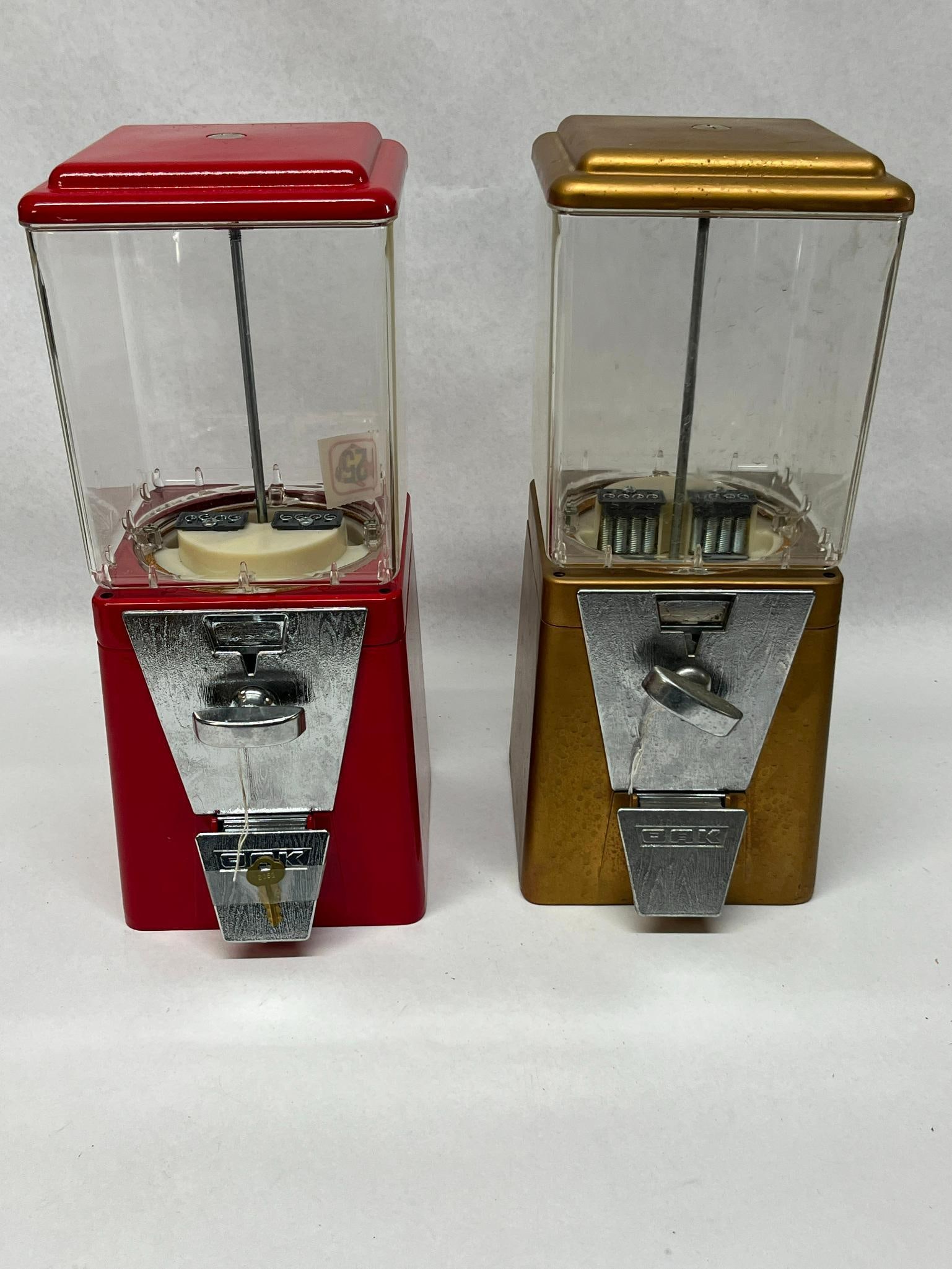 Pair Oak Acorn Vending Machines: This lot features two bulk vending machines produced by Oak Manufacturing Co. Each machine follows the classic Acorn square design, constructed with a die-cast metal base and lid, chrome-plated metal 