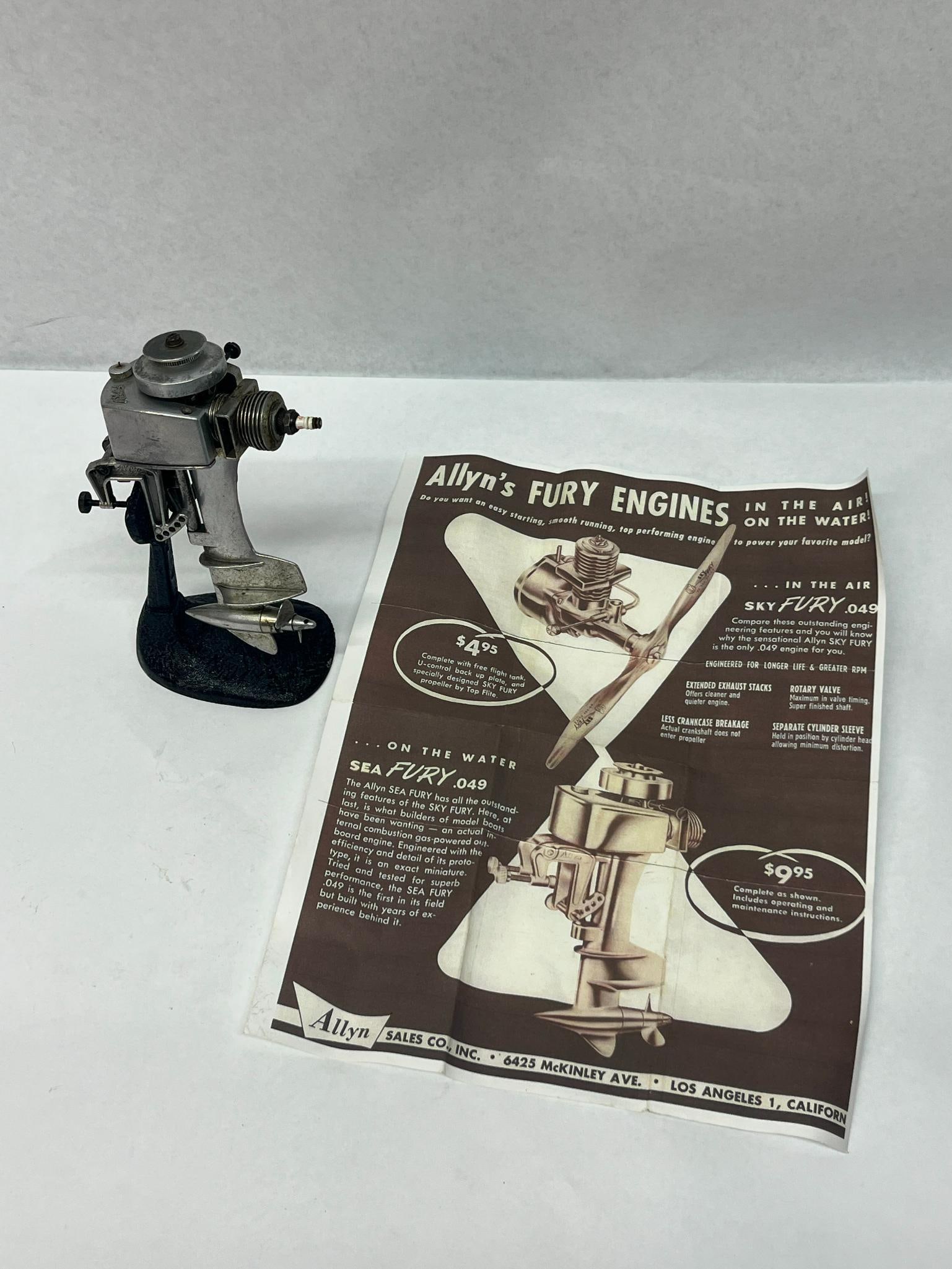 Allyn Sea Fury.049 Outboard w/ Stand: A miniature internal combustion model outboard engine, the Sea Fury.049, produced by Allyn Sales Co., Inc. The engine is constructed from die-cast and machined metal components including steel and