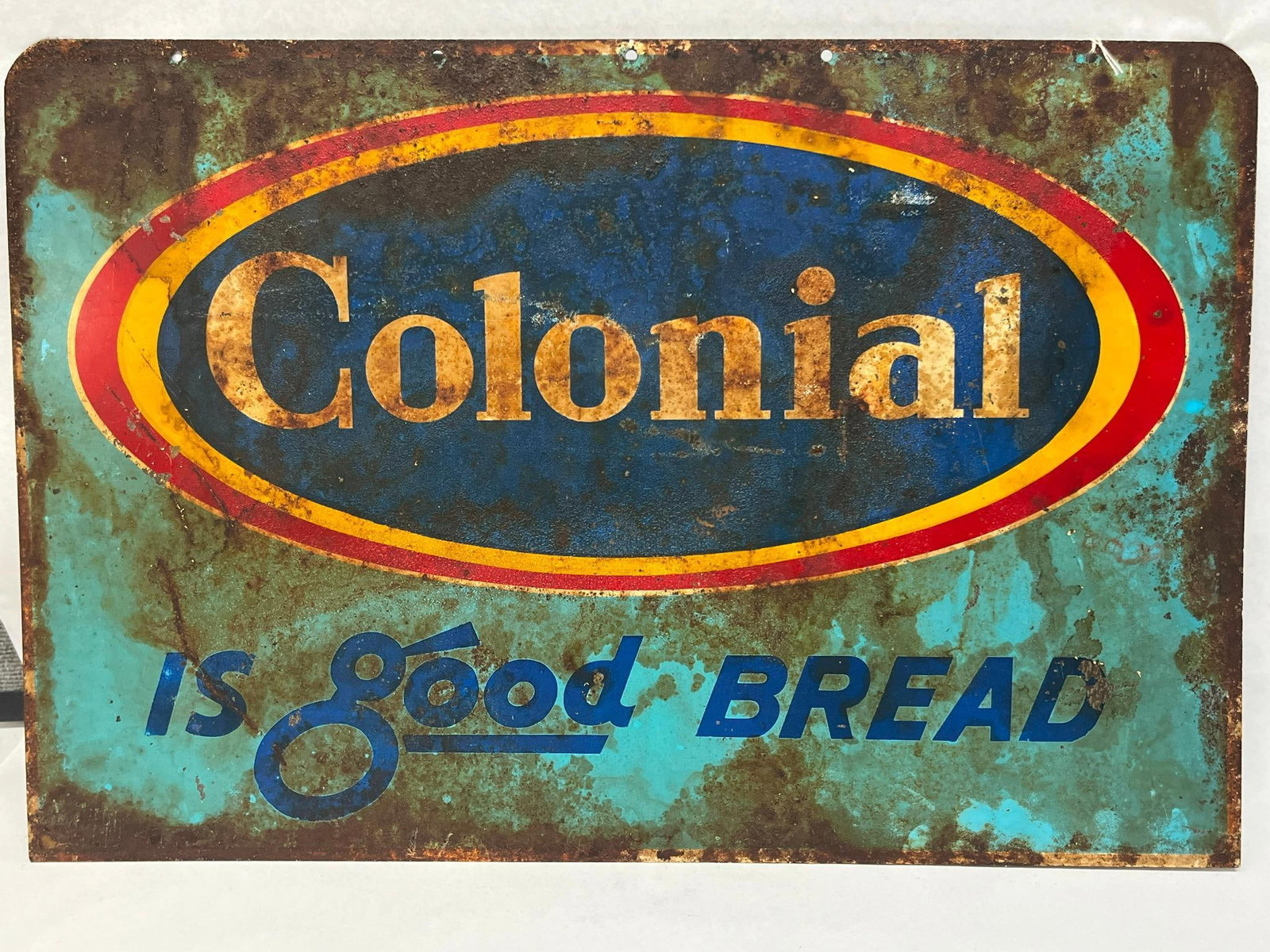 Colonial Bread Metal Advertising Sign: A rectangular metal sign advertising Colonial Bread. The sign is constructed of a single sheet of metal with rounded corners and four pre-drilled mounting holes along the top edge. No maker marks, man