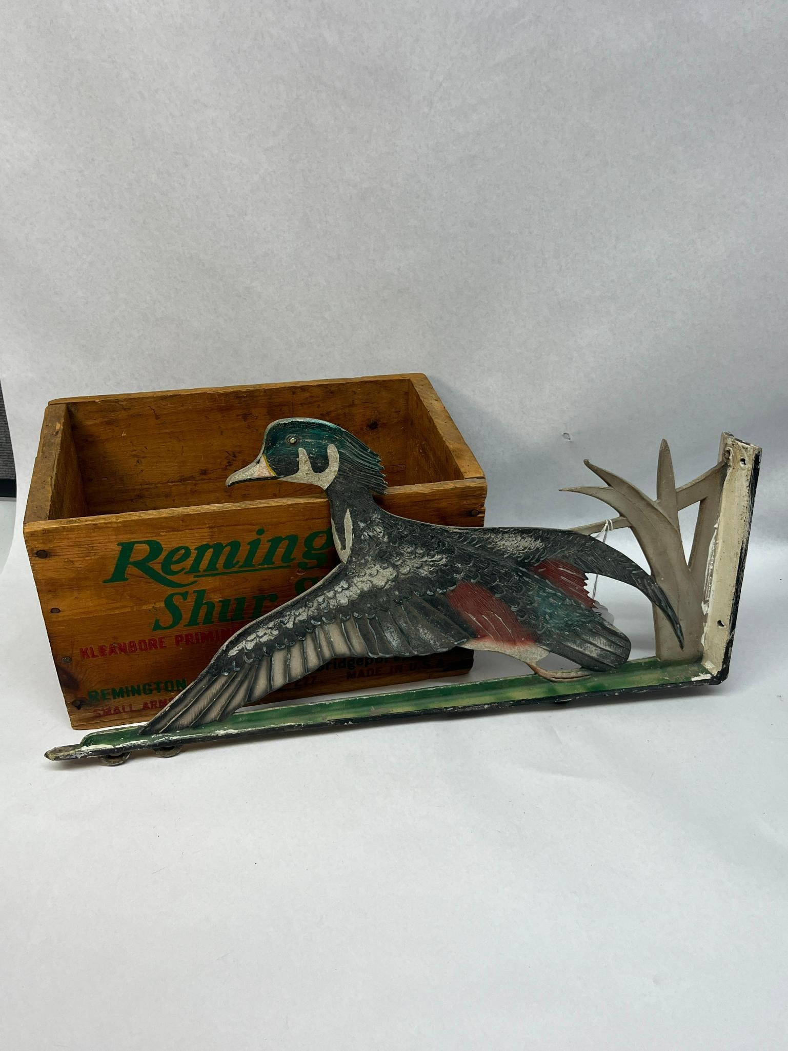Remington Crate & Wood Duck Bracket: Two sporting collectibles including a wooden ammunition shipping crate and a polychrome cast-metal wall bracket. The primary printed text reads Remington Shur Shot. The bottom edges are marked SMALL