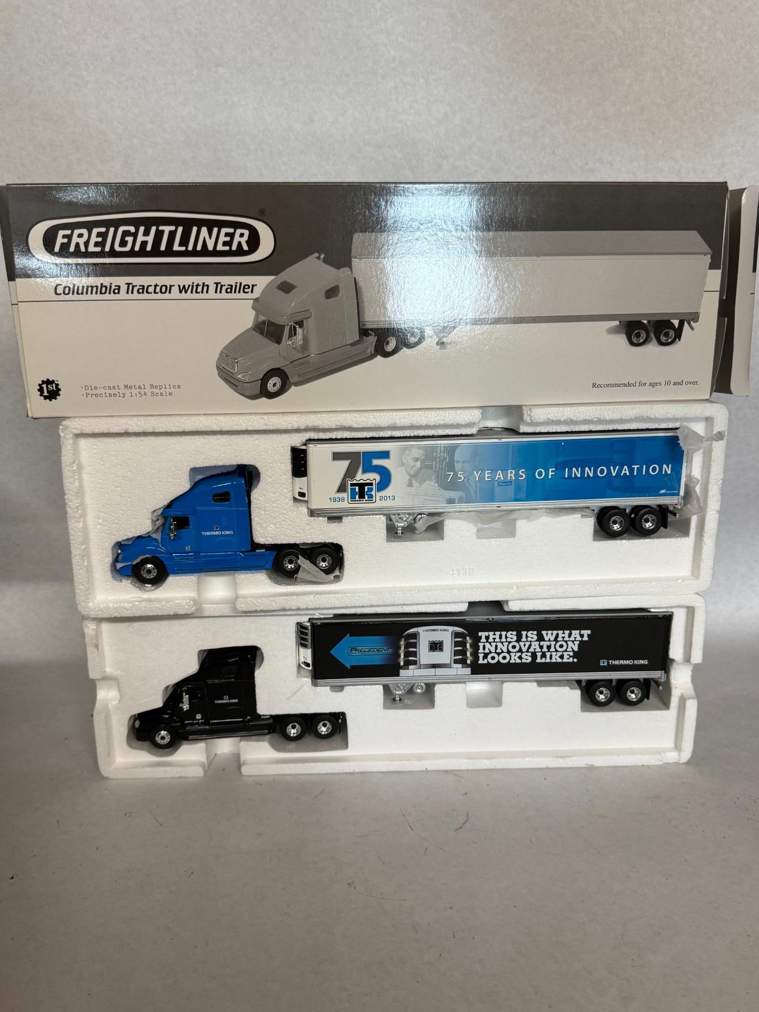 Pair First Gear 1:54 Freightliner Sets: A pair of die-cast metal replica semi-truck sets. The manufacturer is identified as First Gear by the white 1st logo inside a black circle printed on the lower left corner of the box. The trailer is