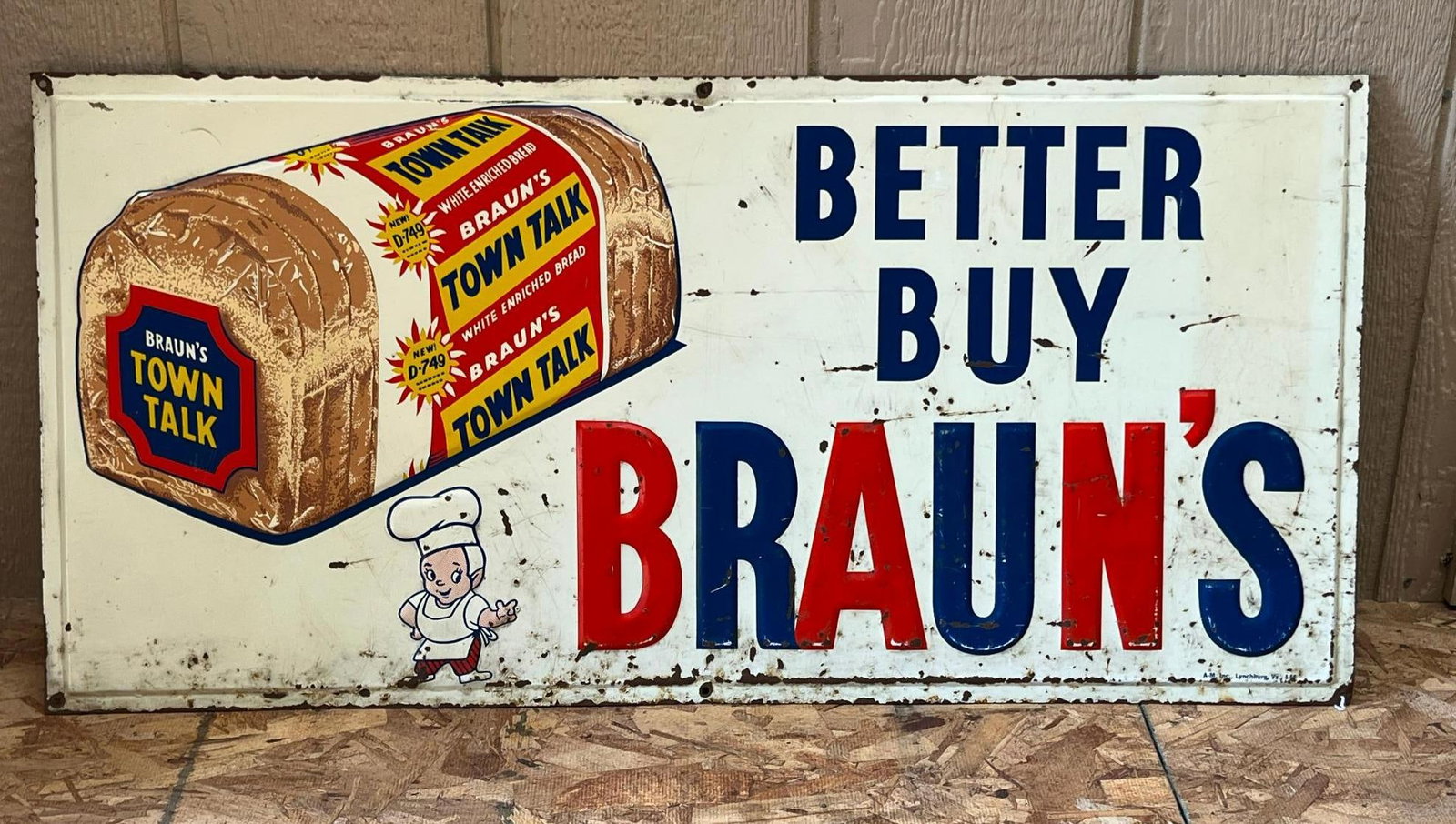 Braun's Town Talk Bread Metal Sign 1954: A rectangular embossed metal advertising sign for Braun's Town Talk Bread. The wrapper graphic includes red and yellow bursts reading NEW! The sign is constructed with six pre-drilled mounting holes