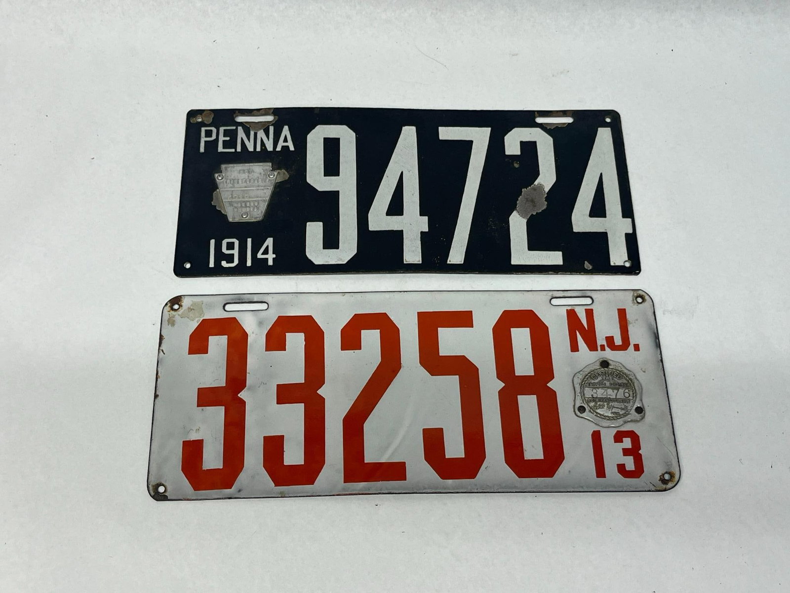 Pair Early 20th C. PA & NJ Lic. Plates: This lot consists of two early 20th-century automotive license plates from Pennsylvania and New Jersey. Both plates are single-sided and constructed from porcelain enamel on steel. The Pennsylvania