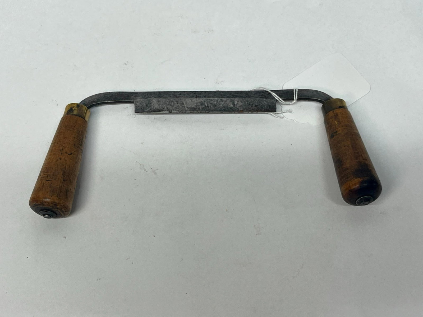 Steel Drawknife w/ Turned Wood Handles: This antique woodworking tool is a drawknife, designed for shaving and shaping wood. The tool is constructed with a straight, forged steel blade featuring a single-bevel cutting edge. Each handle is