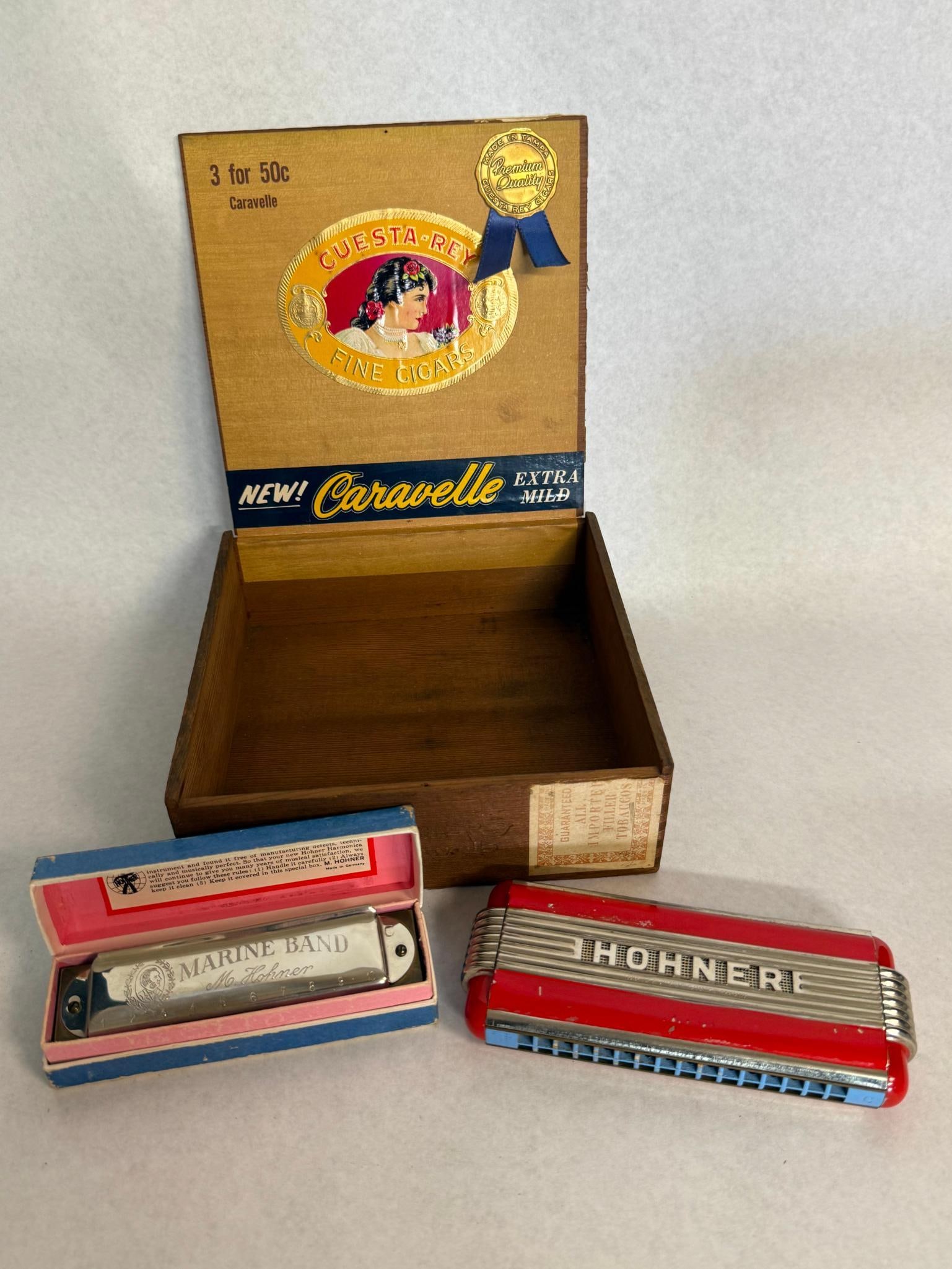 Hohner Harmonicas, Cuesta-Rey Cigar Box: A German-made collection featuring two Hohner harmonicas and a cigar box. It features chrome-plated metal cover plates, brass reed plates, and a wooden comb. The top plate is stamped MARINE BAND and